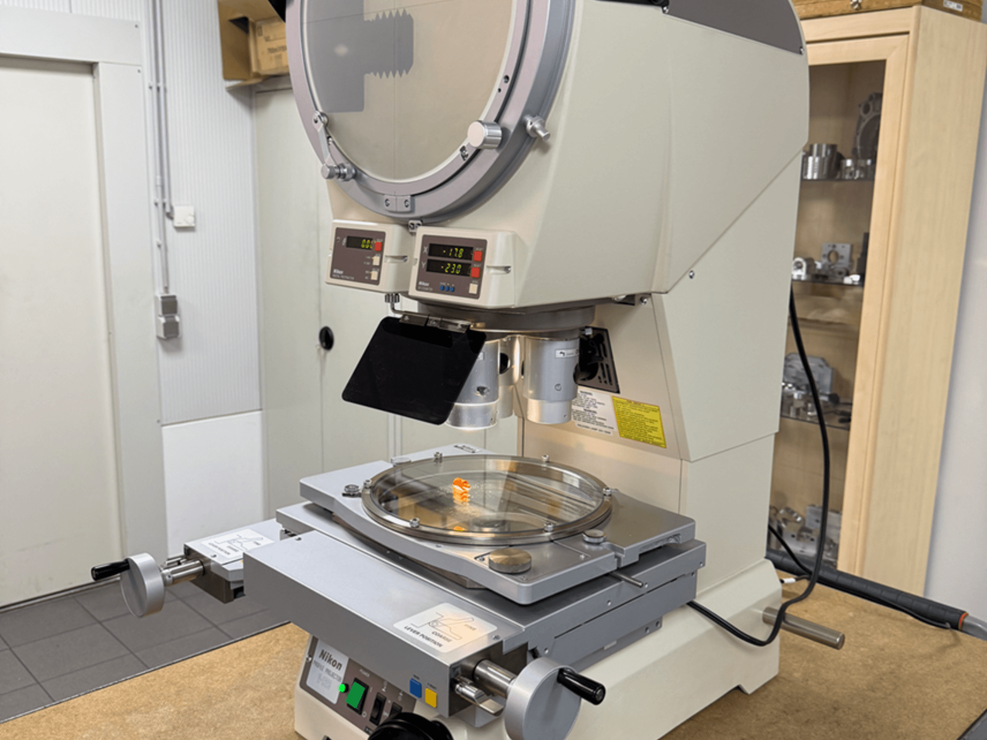 Microscopio modelo Nikon desde una vista frontal, con pantallas digitales, una platina ajustable y una placa de cristal circular.