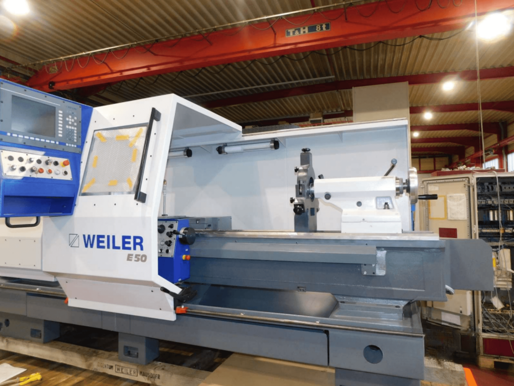 Máquina de torneado horizontal Weiler E50, vista frontal, con panel de control, husillo y bancada de precisión con accesorios.