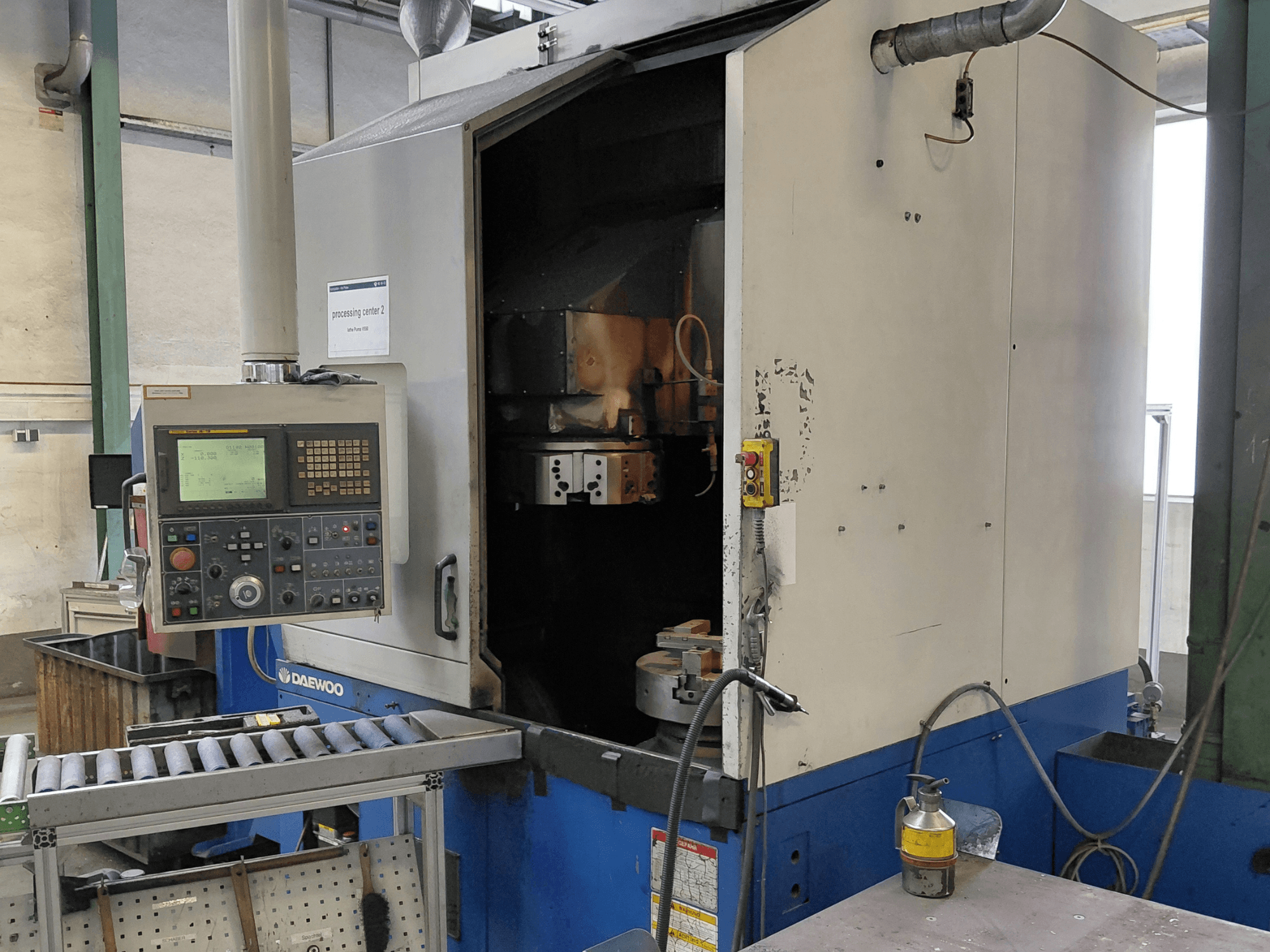 Máquina de torneado vertical Daewoo Puma V550, vista frontal que muestra el panel de control, el husillo y la conexión de refrigerante.