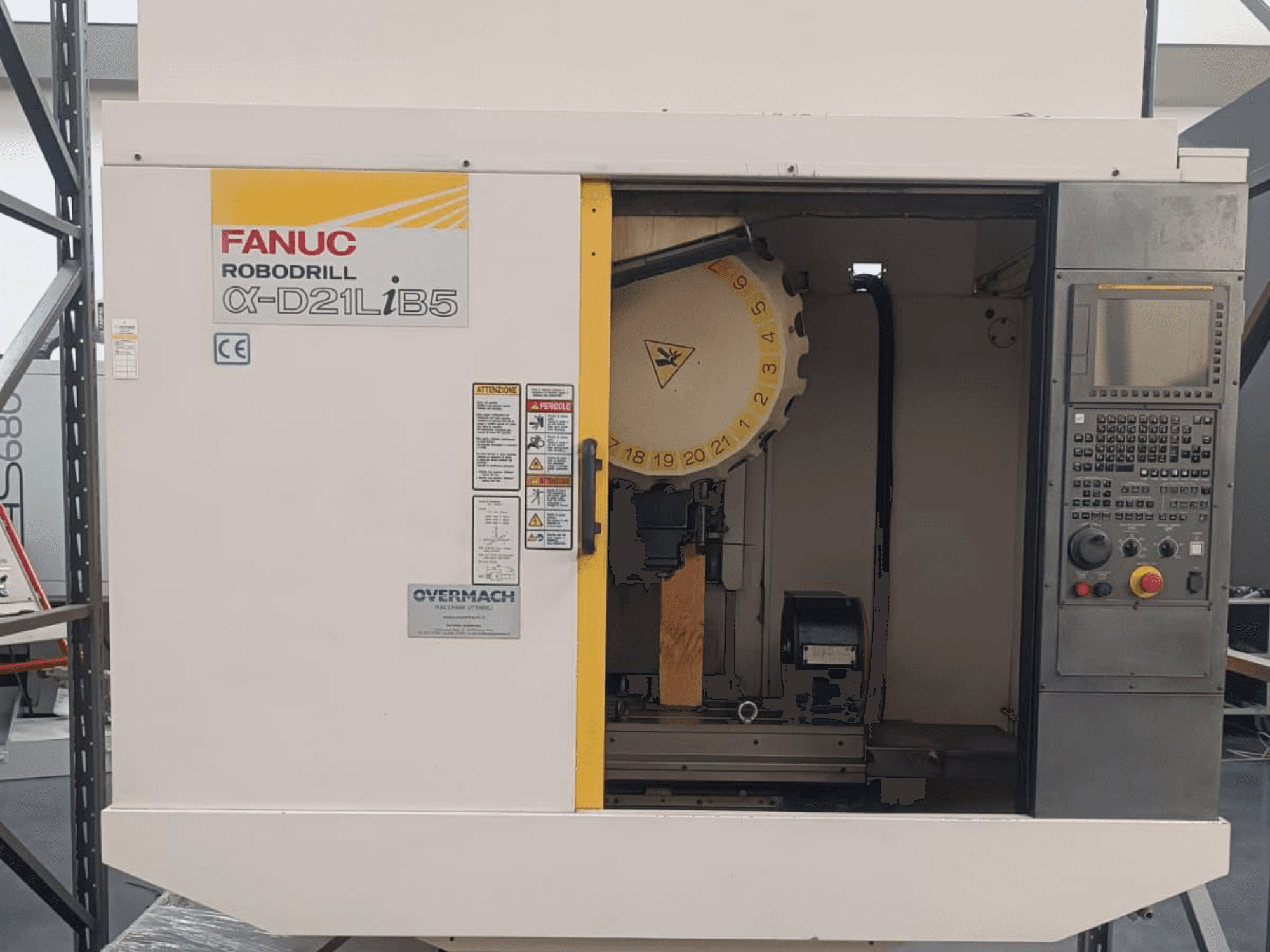 FANUC Robodrill α-D21LiB5, vista frontal; máquina CNC con portaherramientas, panel de control y advertencias de seguridad visibles.