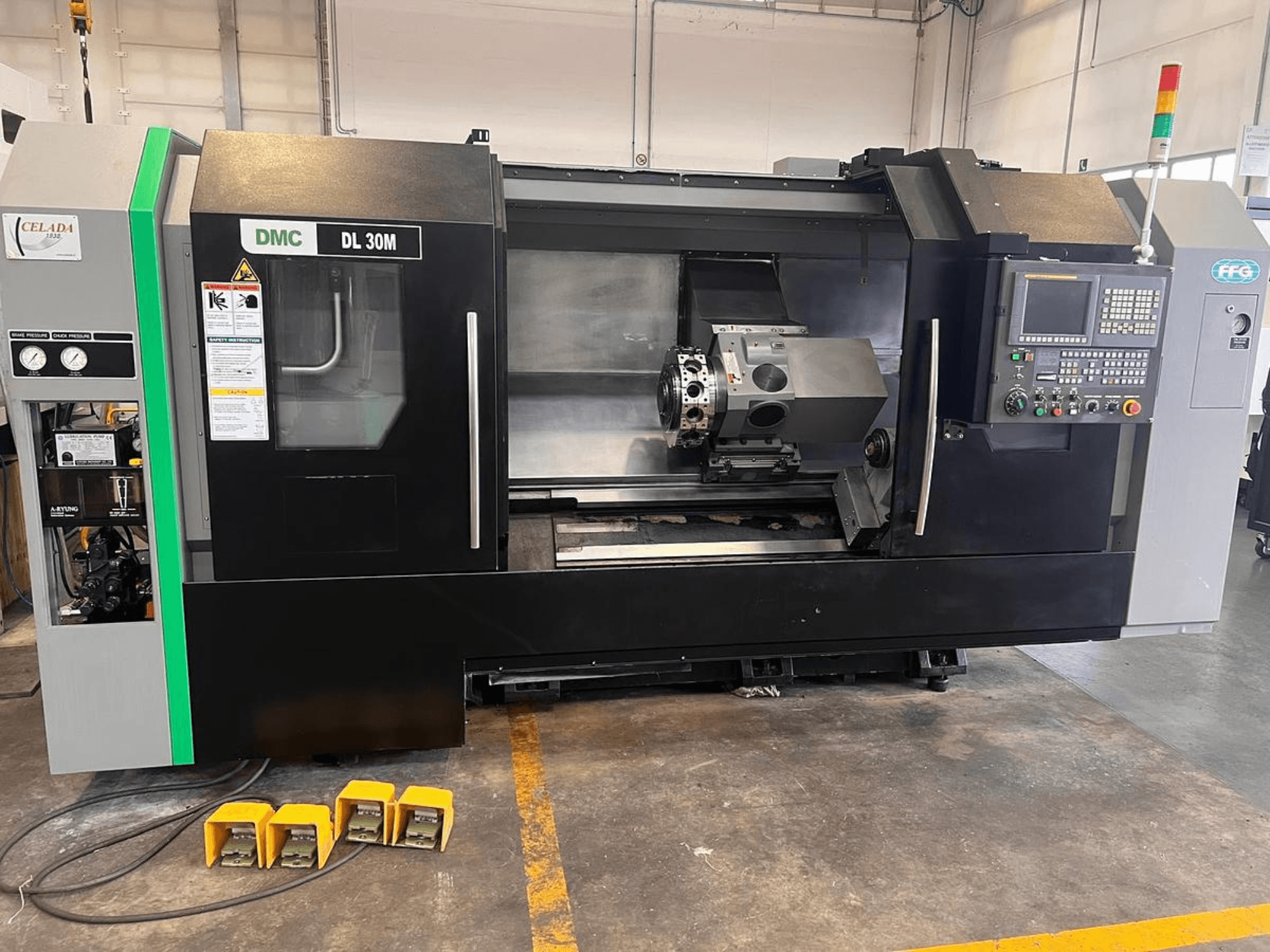 Máquina CNC DMC DL 30M con una vista lateral que muestra los controles, el husillo y tres pedales en el suelo.