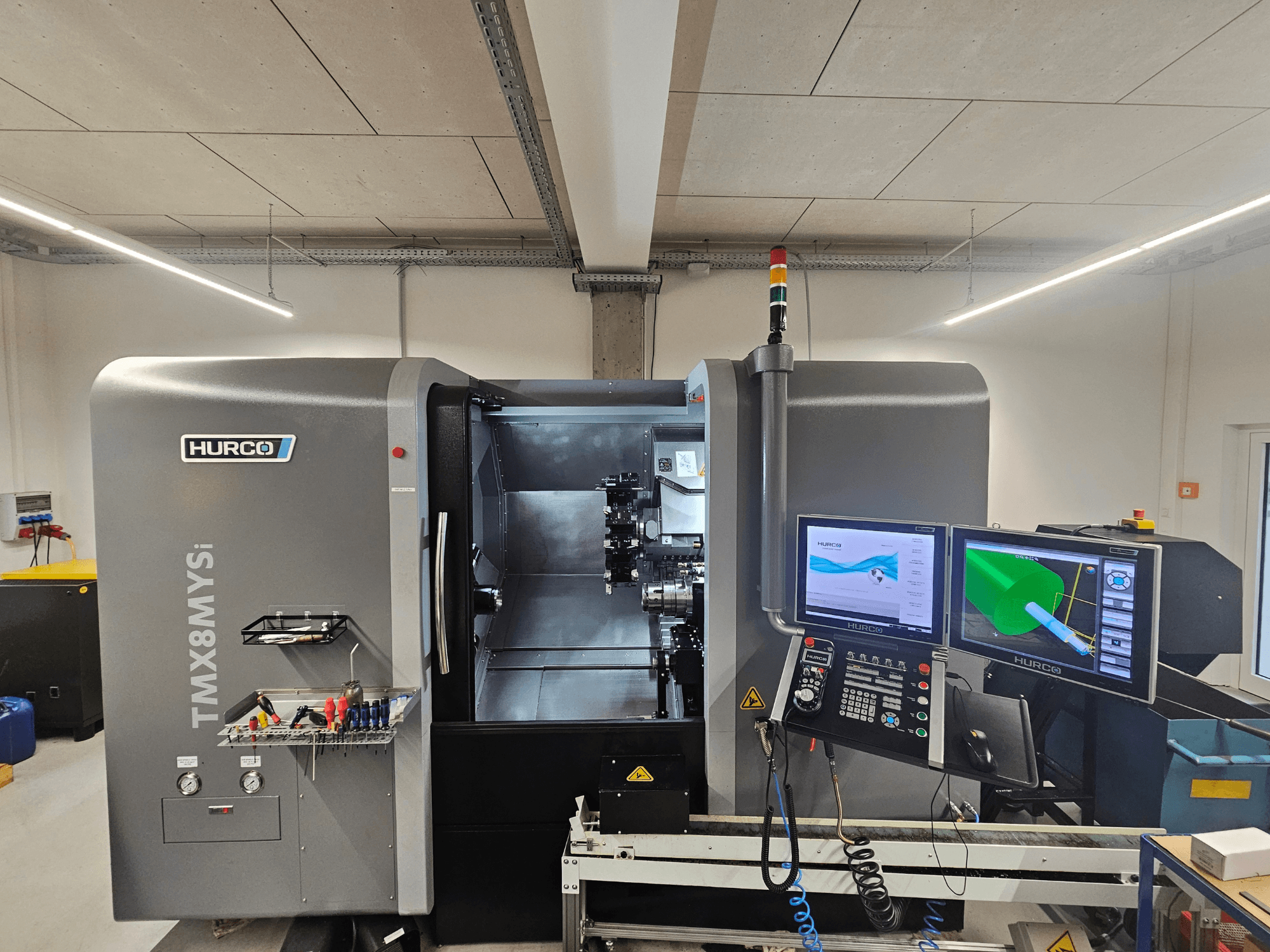 Centro de torneado y fresado Hurco TMX 8 MYSi en un taller, con monitores dobles, panel de control y herramientas en el lateral.