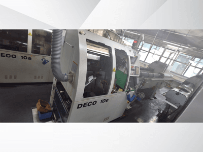 Máquina CNC DECO 10e en vista lateral, con panel de control, interior verde y manguera de escape conectada.