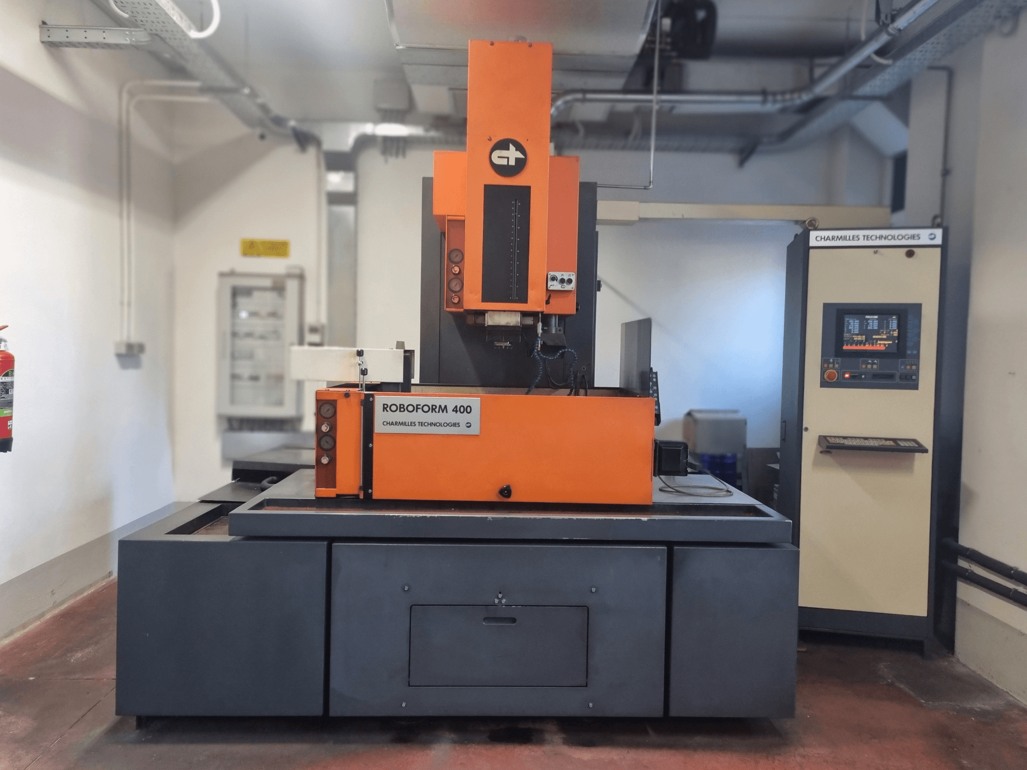 Máquina Roboforn 400 de Charmilles Technologies, vista frontal, con diseño naranja y gris, panel de control digital visible.