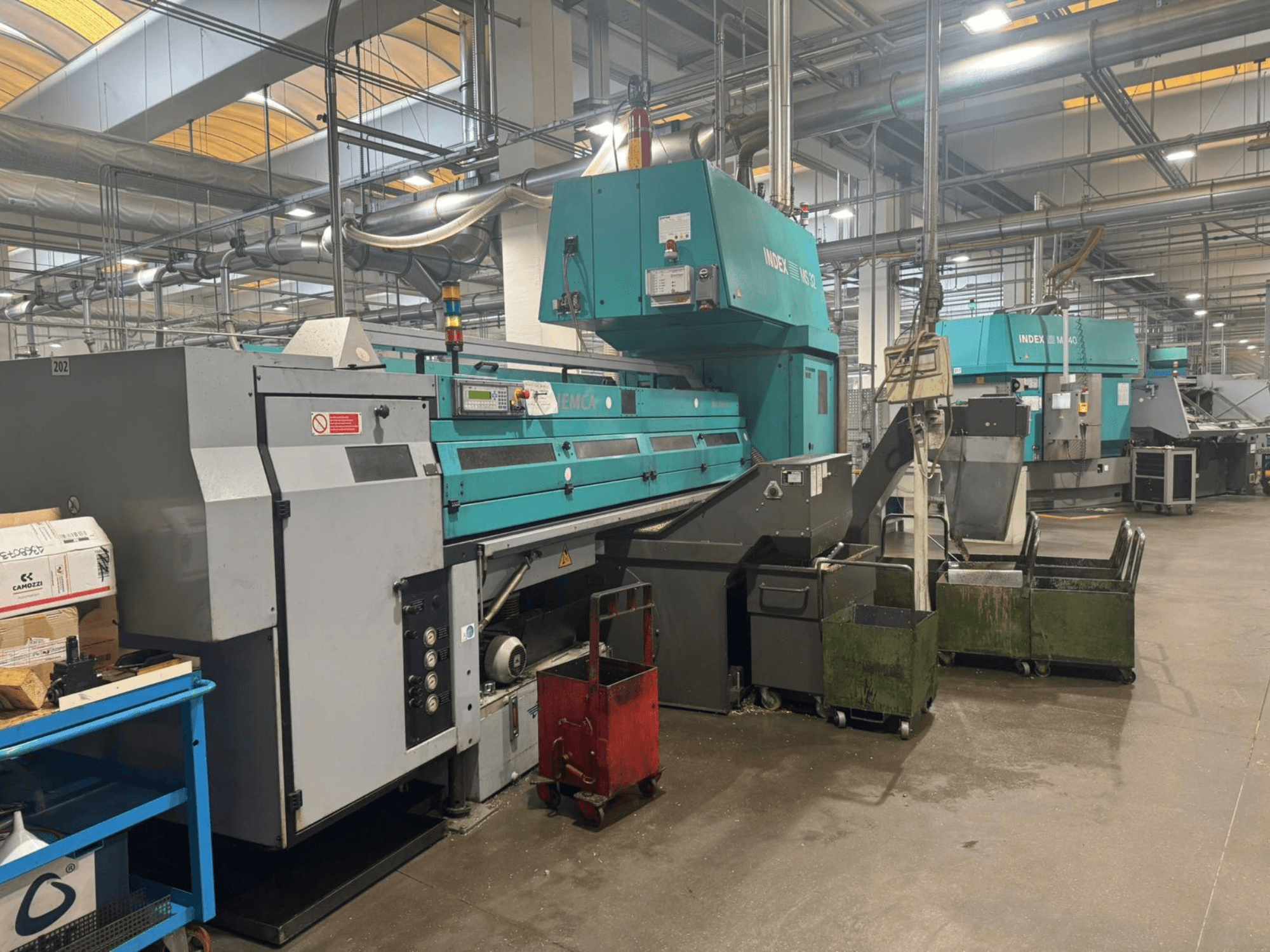 Máquina de torneado multihusillo, INDEX MS32C, vista frontal que muestra los controles y el área operativa en un entorno de taller.