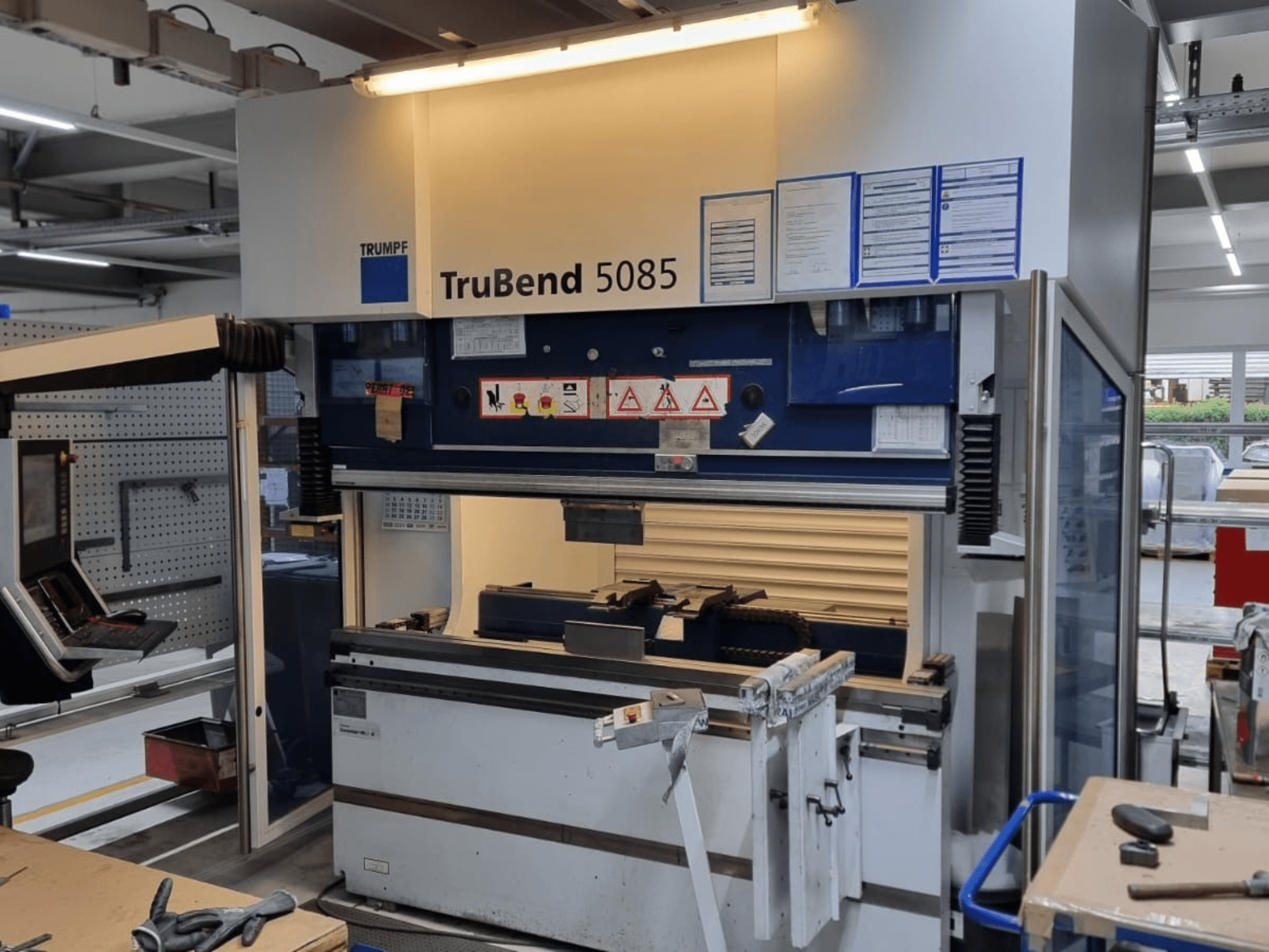 TRUMPF TruBend 5085 bending machine, front view, showing control panel, operating station, and safety warnings inside workshop.