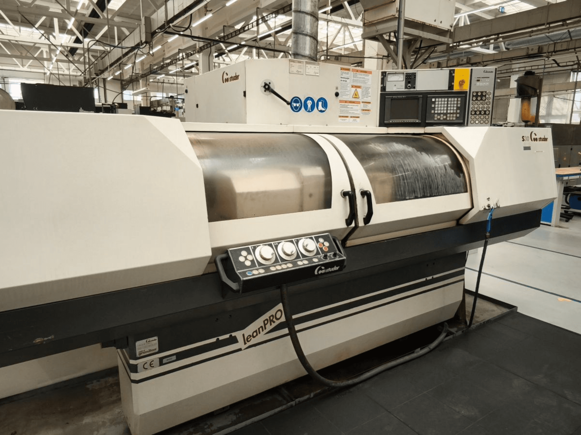 Rectificadora cilíndrica STUDER S30 LEAN PRO, vista lateral, mostrando el panel de control y la cubierta de la muela abrasiva en un entorno industrial.