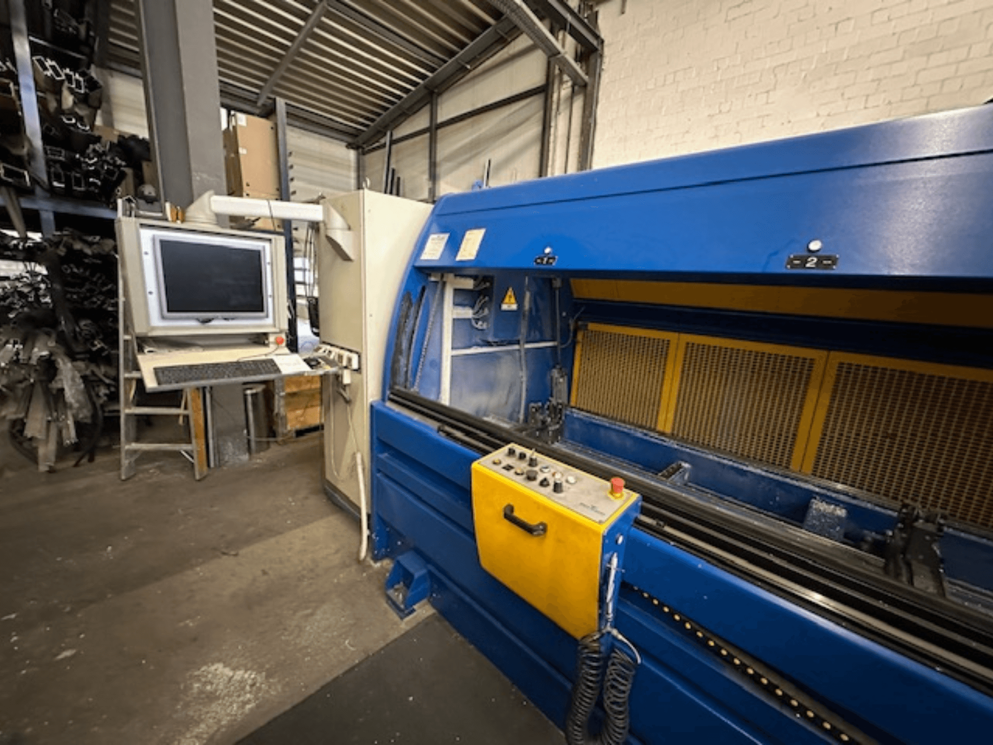 Vista frontal del SCHÜCO Profilbearbeitungscenter 299 650, un centro de mecanizado universal con controles y estación de trabajo informatizada.