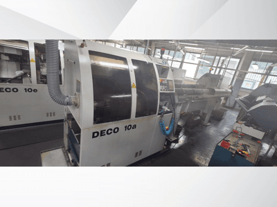 Máquina CNC DECO 10a en un taller, mostrando la vista frontal, el panel de control y el sistema de escape. Construcción robusta y herramientas de precisión.