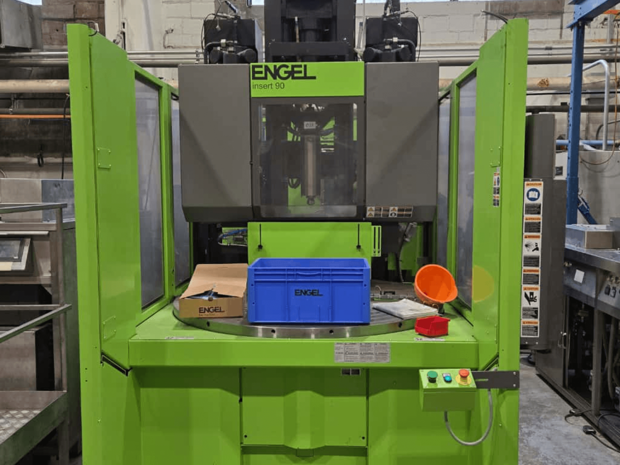 Green ENGEL Insert 90 injection molding machine front view, featuring blue container and control panel with buttons.