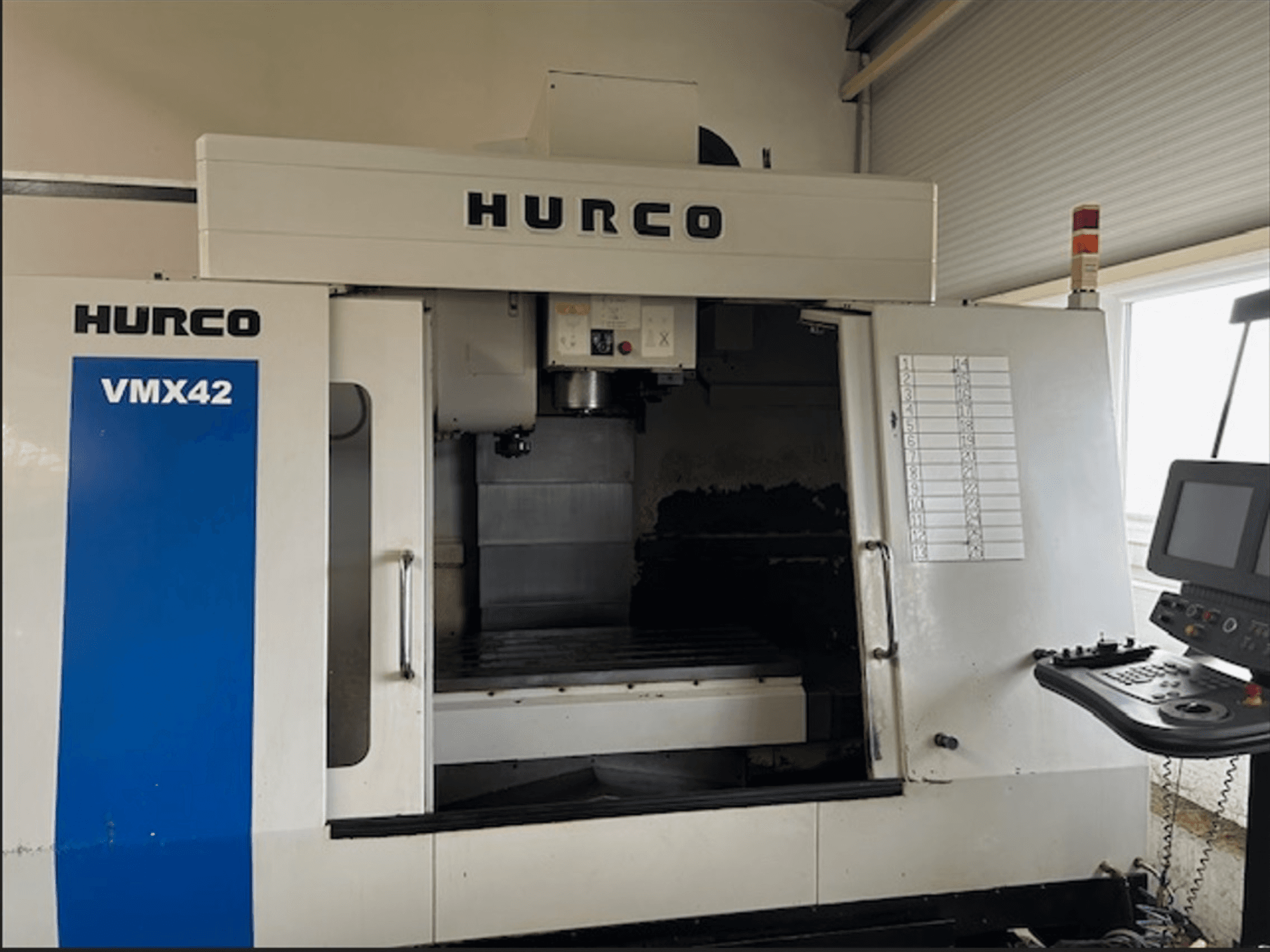 Fresadora CNC Hurco VMX42, vista frontal, presenta panel de control y espacio de trabajo abierto para operaciones de mecanizado.