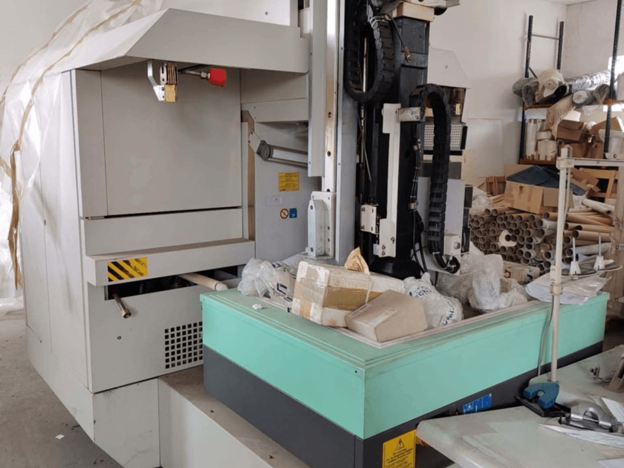 Máquina de electroerosión por penetración AGIE AGIETRON INTEGRAL 2, vista frontal, mostrando el panel de control, la mesa de trabajo y el desorden circundante.