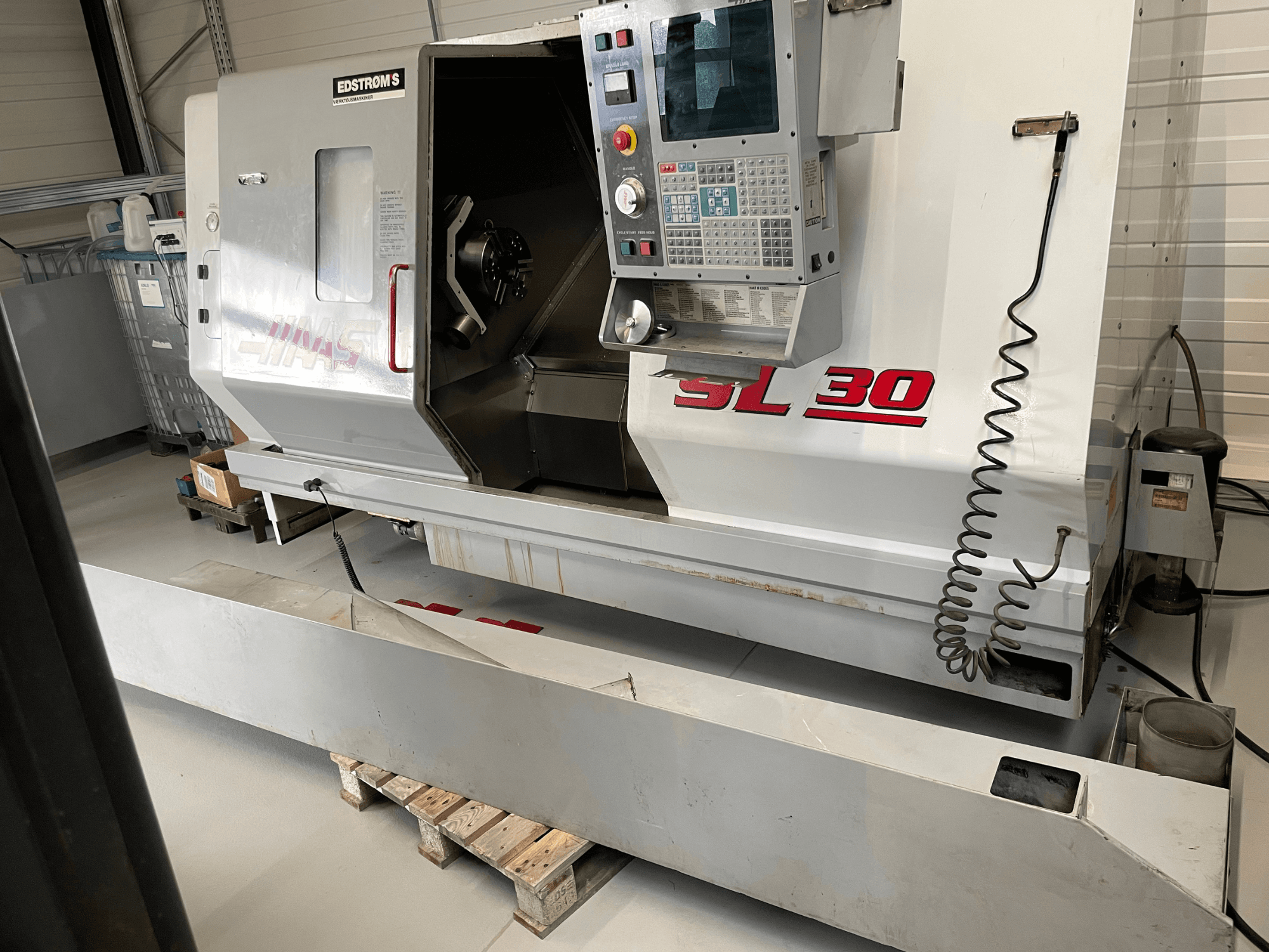 Torno CNC Haas SL 30 en un taller, vista lateral, con panel de control y husillo abierto para tareas de mecanizado.