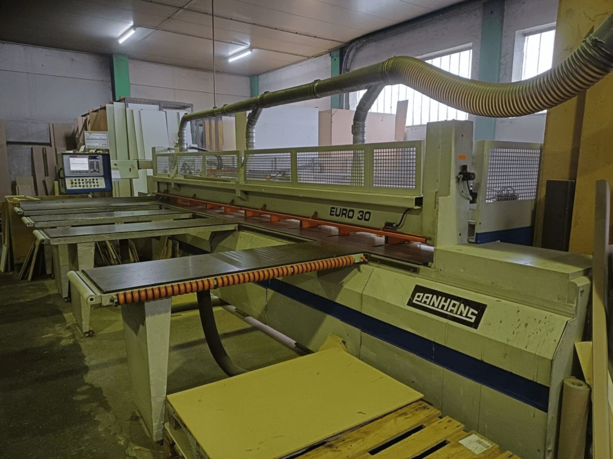 Vista frontal de la seccionadora PANHANS EURO 30 con panel de control, mesa de corte y manguera de aspiración de polvo en un taller.