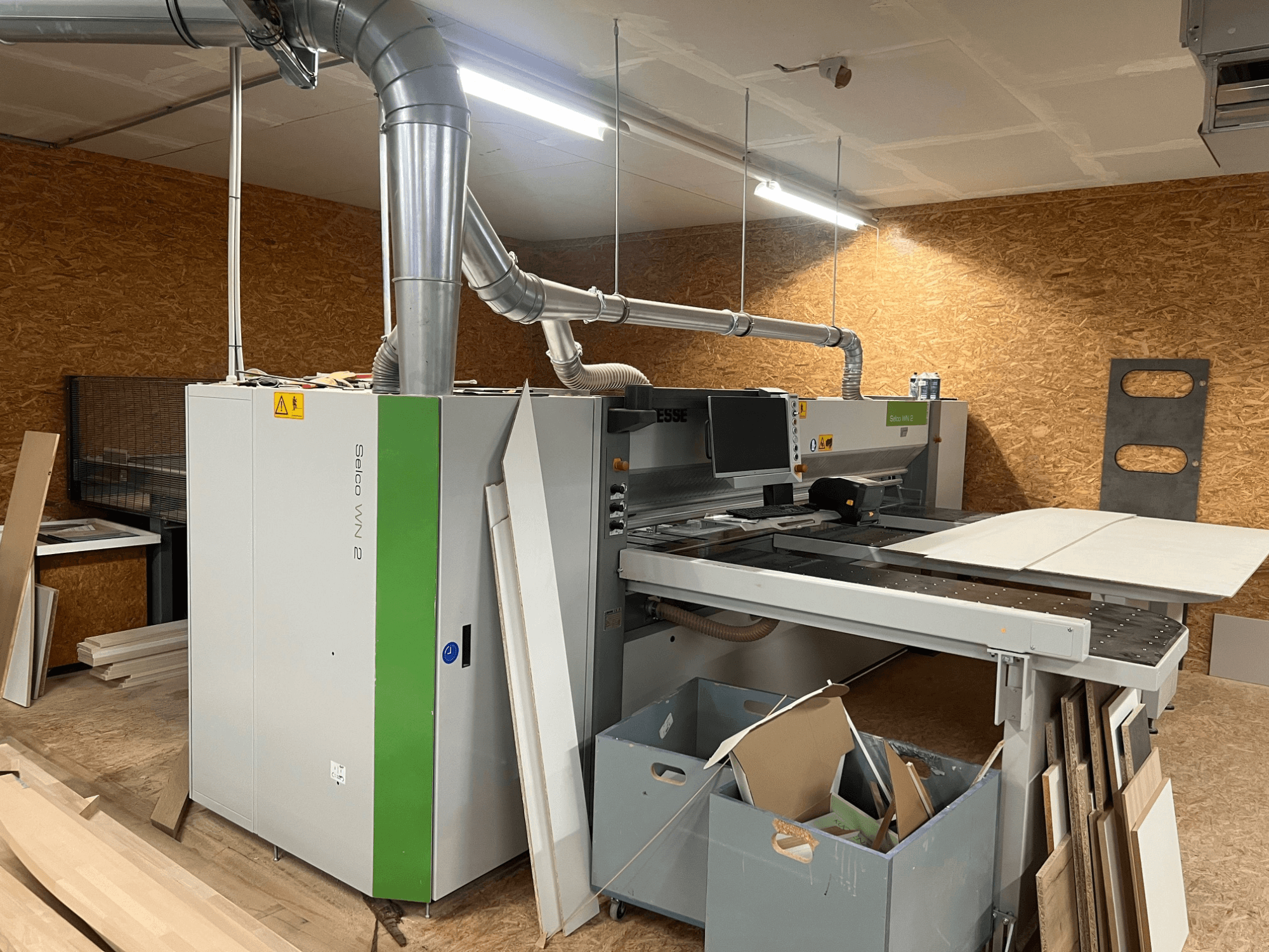 Seccionadora BIESSE Selco WN 2 en un taller, con una gran mesa de corte y sistema de aspiración de polvo, vista lateral.