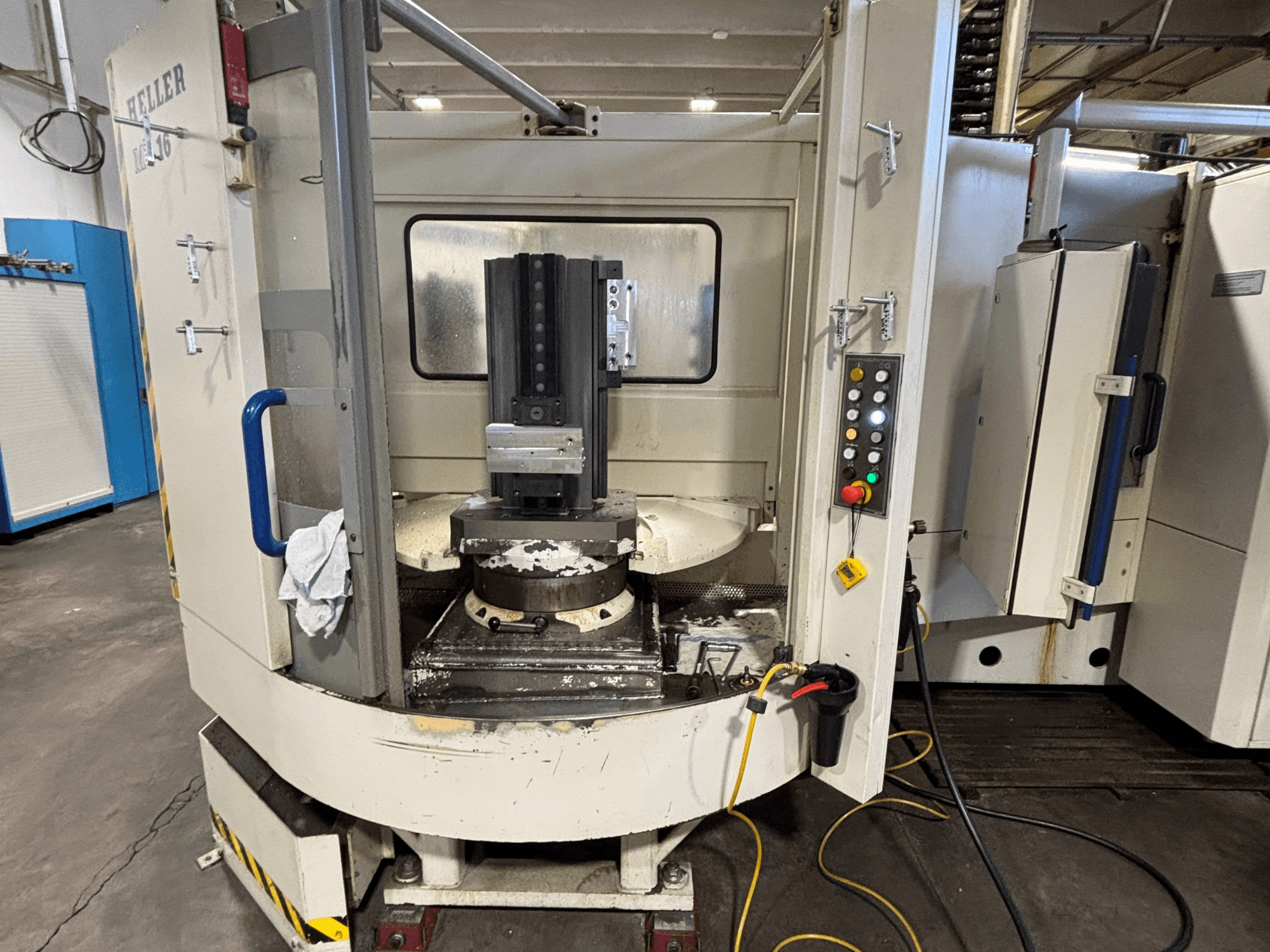 Centro de mecanizado Heller, modelo vertical, vista frontal que muestra el husillo, el panel de control y la mesa de trabajo con el equipo acoplado.