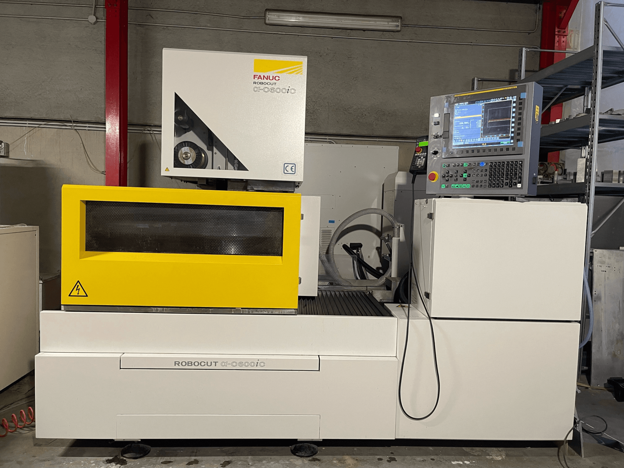 FANUC Robocut α-C600iC, vista lateral de la máquina CNC con cubierta de seguridad amarilla y panel de control, mostrando la capacidad de corte de precisión.