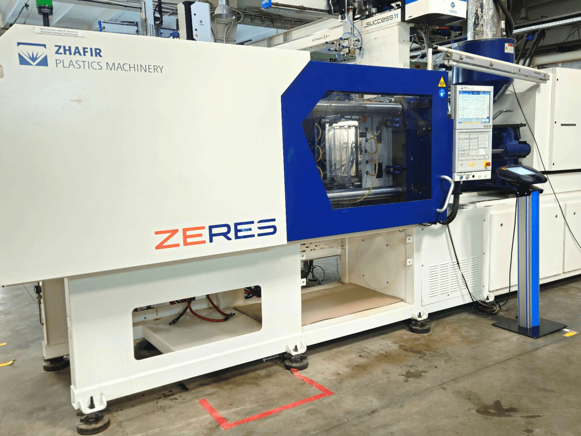 Zhafir Zeres injection molding machine in front view, featuring control panel and transparent molding area.
