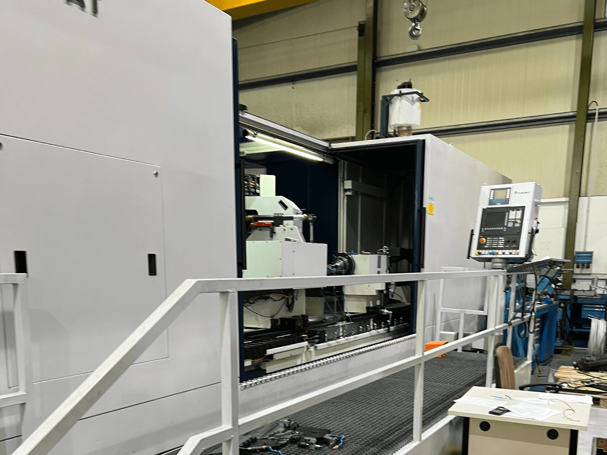 Centro de mecanizado CNC con vista lateral abierta, mostrando los controles, el portaherramientas y el componente principal del interior. Detalles de la marca no visibles.