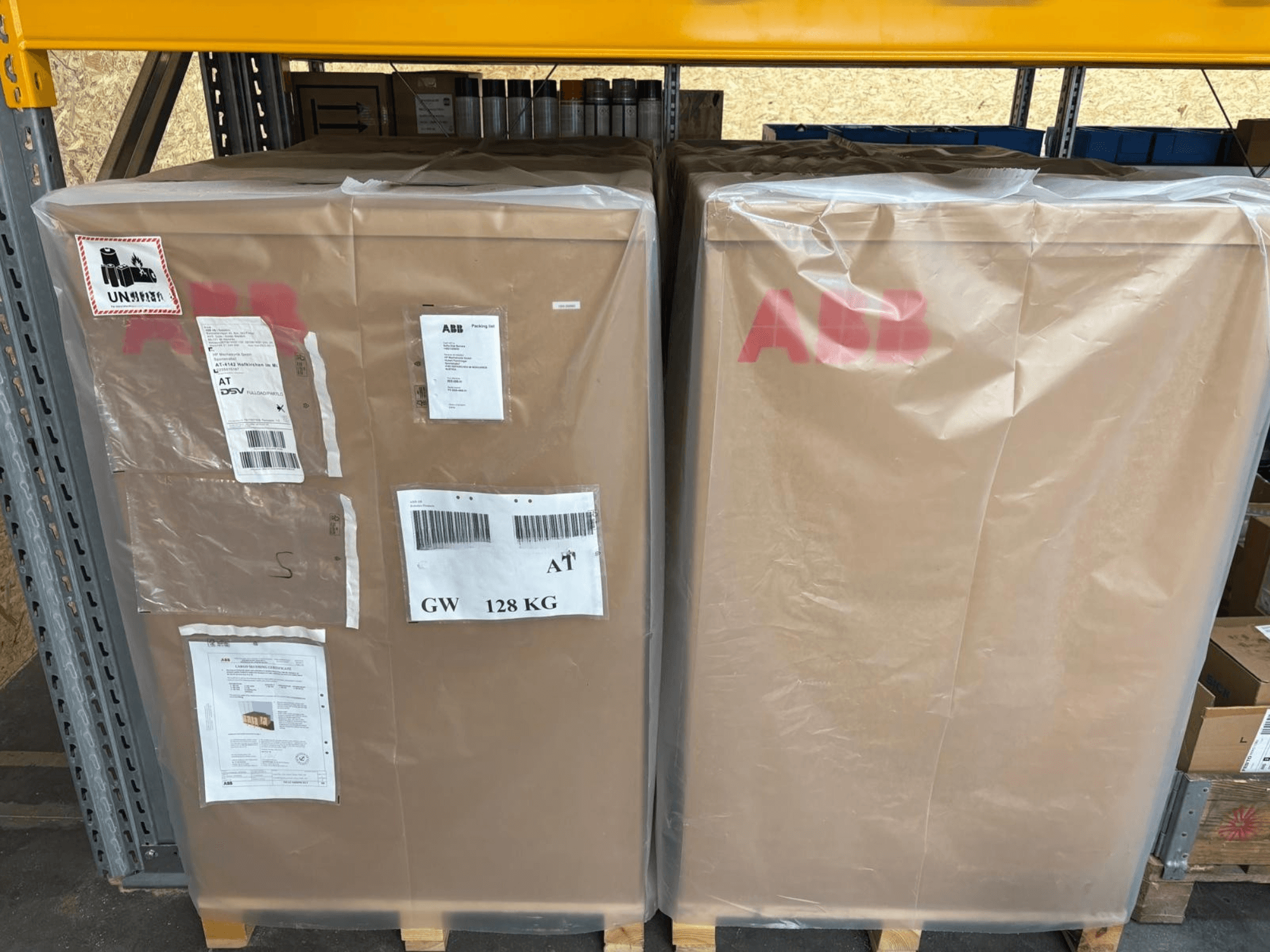 Two large cardboard boxes wrapped in plastic, marked "ABB," with shipping labels and a weight of 128 kg, front view.