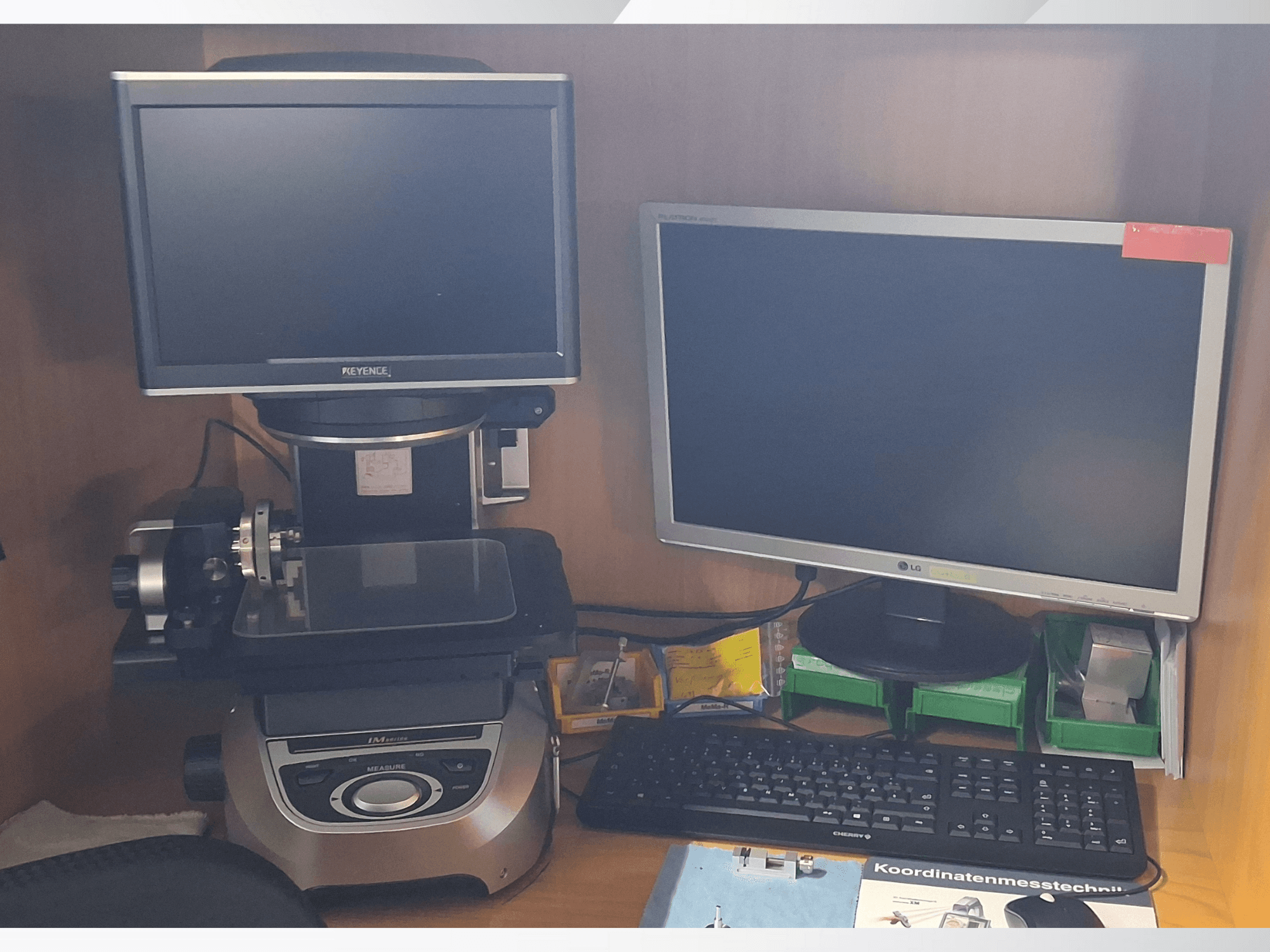 Sistema de medición Keyence con dos monitores (uno LG, otro Keyence) y un teclado, visto de frente.