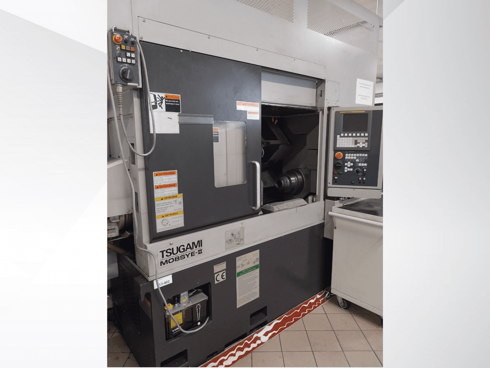 Torno CNC Tsugami M08SY-II, vista frontal, mostrando el panel de control, el husillo y la zona de carga. Incluye avisos de seguridad y etiqueta de marca.