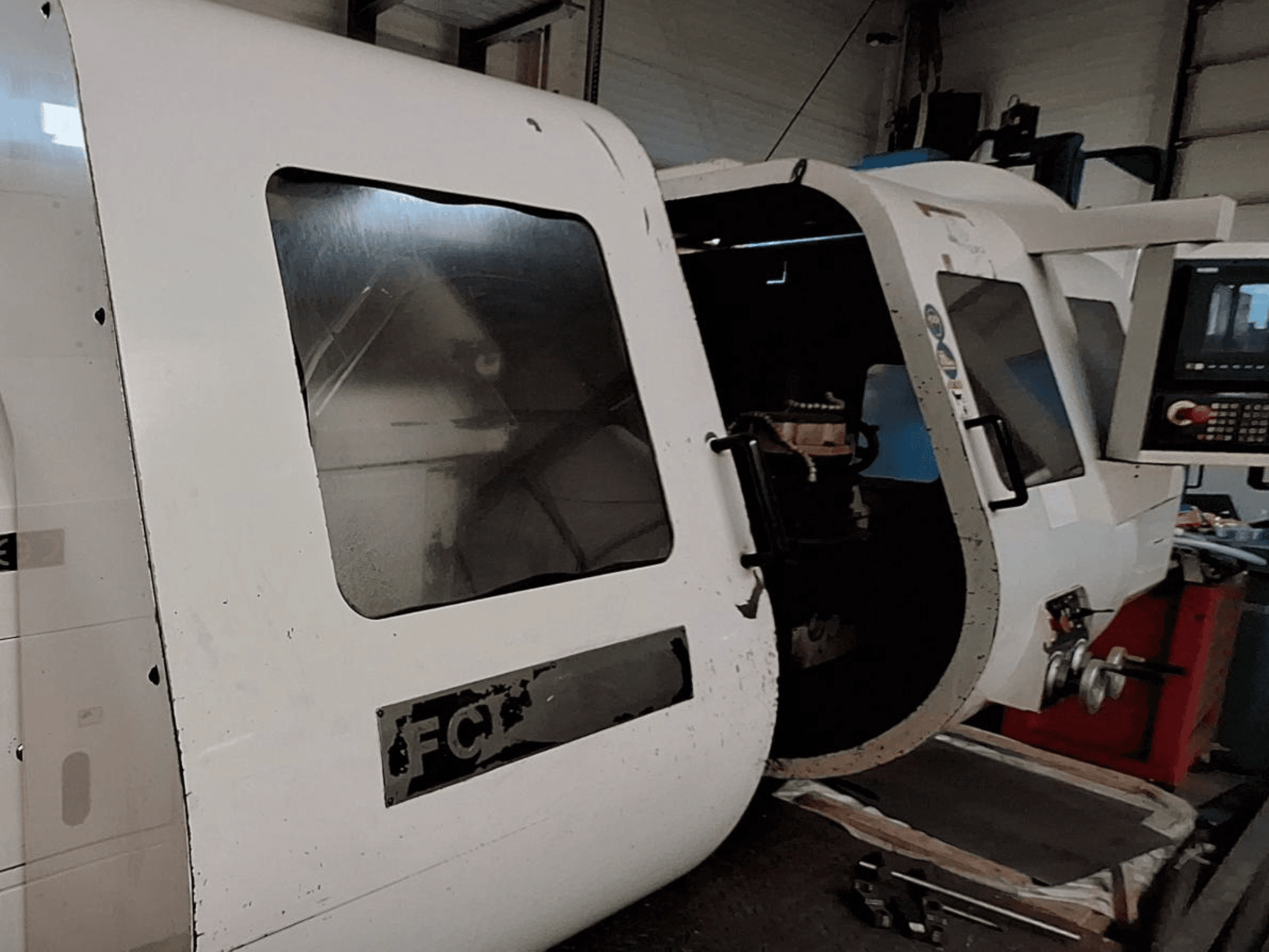 White CNC machine with visible control panel and open door, showcasing interior components; front view. Brand: FCT.