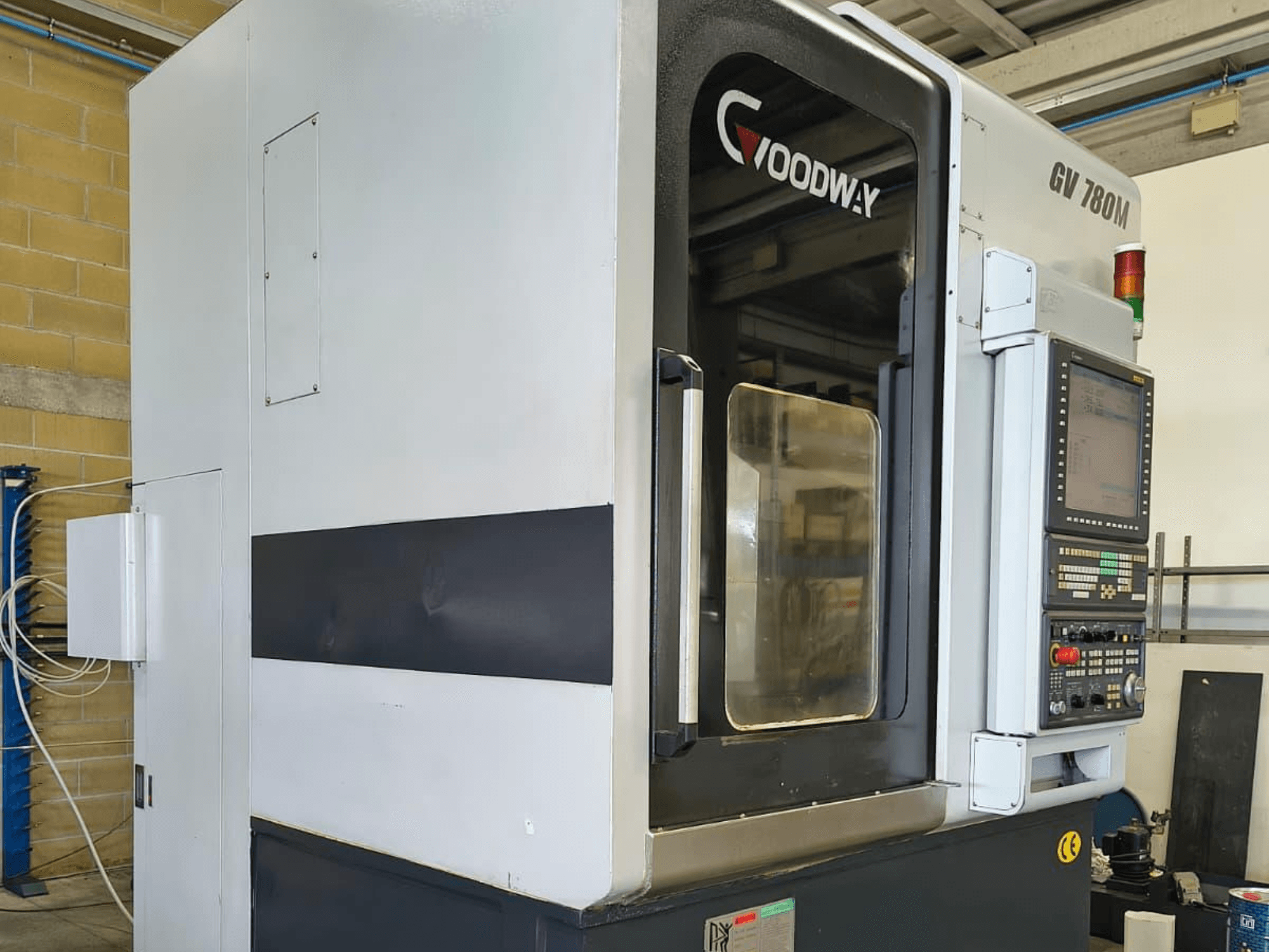 Tornos verticales Goodway GV 780 M, vista lateral, mostrando el panel de control, las características de seguridad y el diseño exterior limpio.