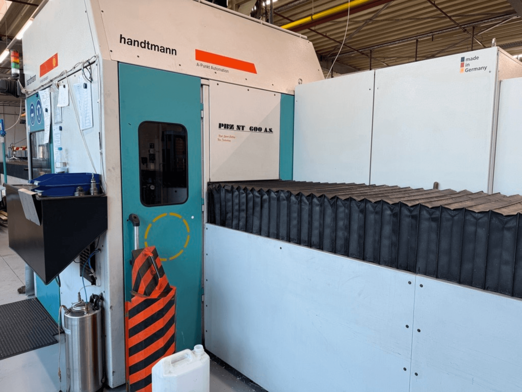 Vista frontal de la fresadora de pórtico Handtmann PBZ NT 600 AS, con superficie de trabajo oscura y barreras de seguridad.