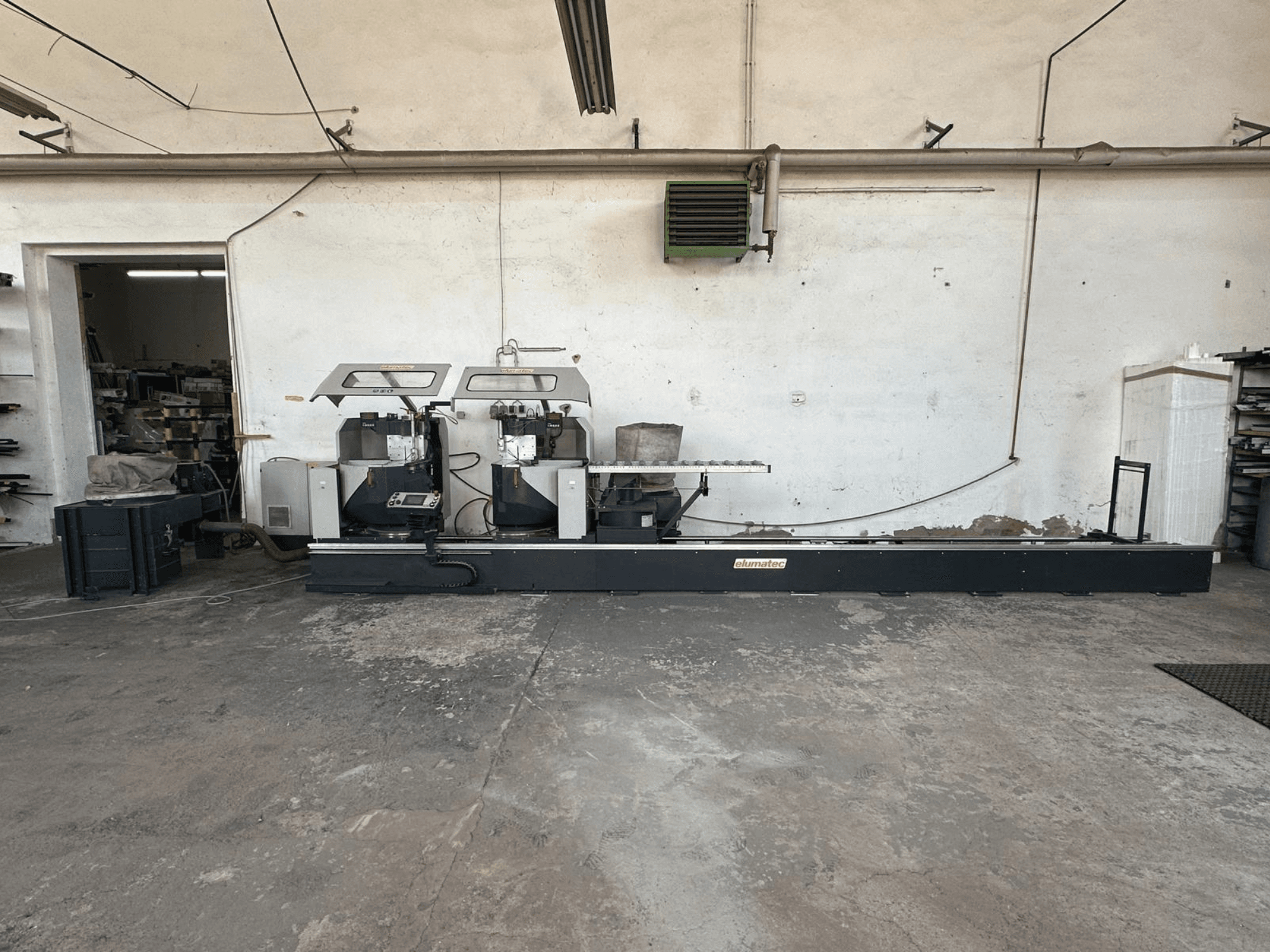 Sierra circular para metales Elumatec DG 244 en un taller, vista lateral mostrando las sierras dobles y los controles de funcionamiento sobre una base robusta.