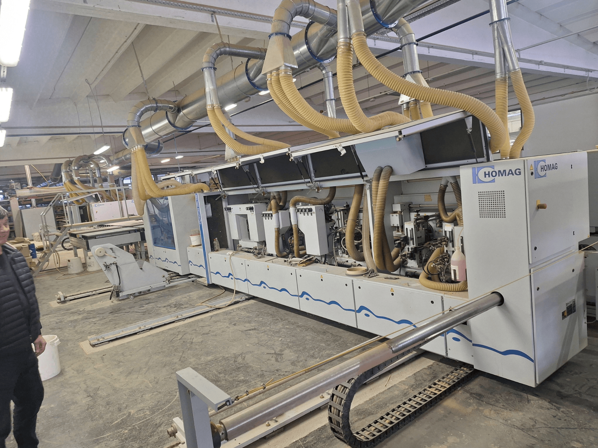 HOMAG woodworking machine in a factory setting, front view showing multiple spindles and dust extraction system.