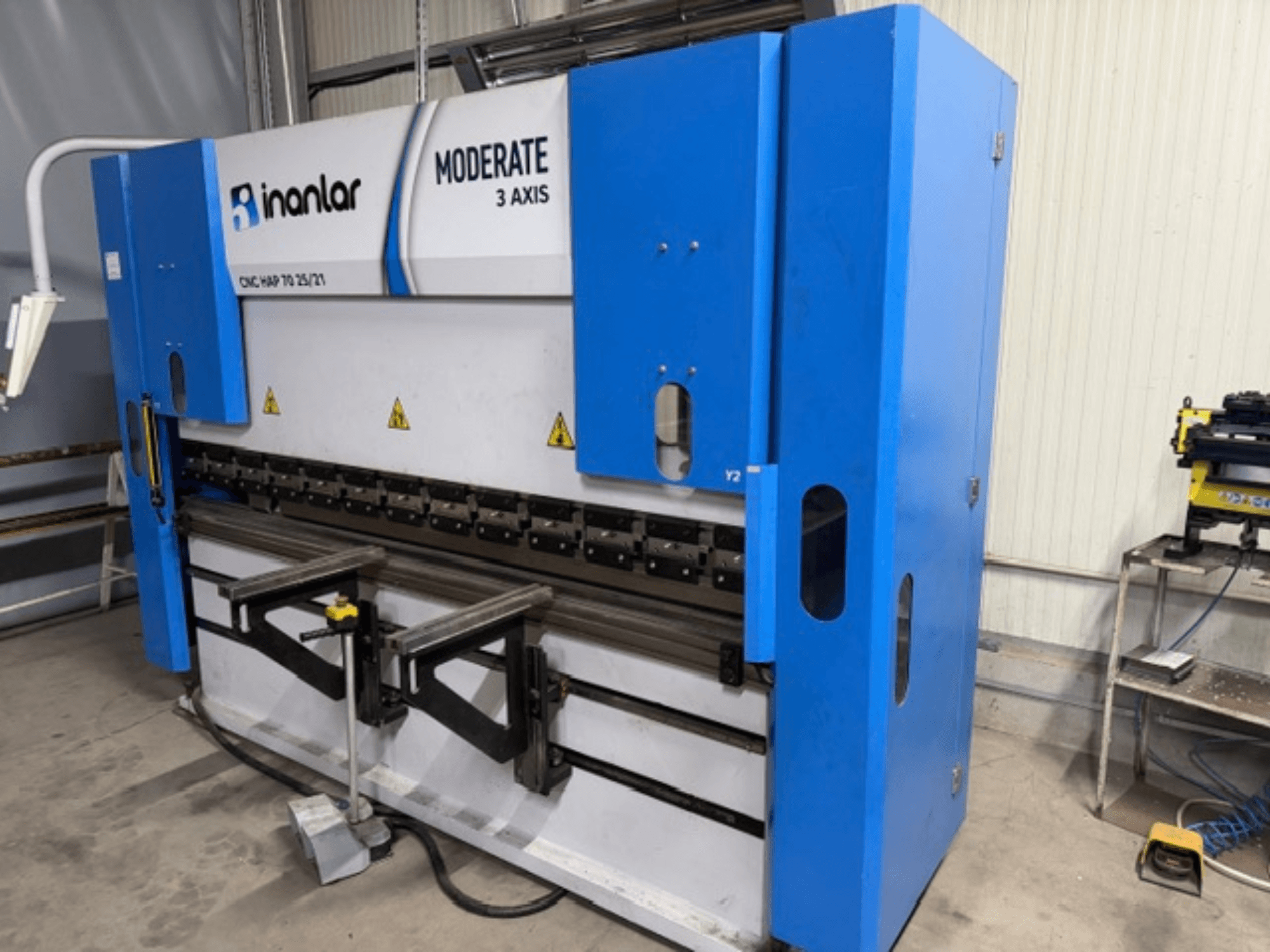 Máquina CNC de 3 ejes Inanlar Moderate en azul, vista frontal, presenta palancas de control y etiquetas de seguridad visibles en el cuerpo.