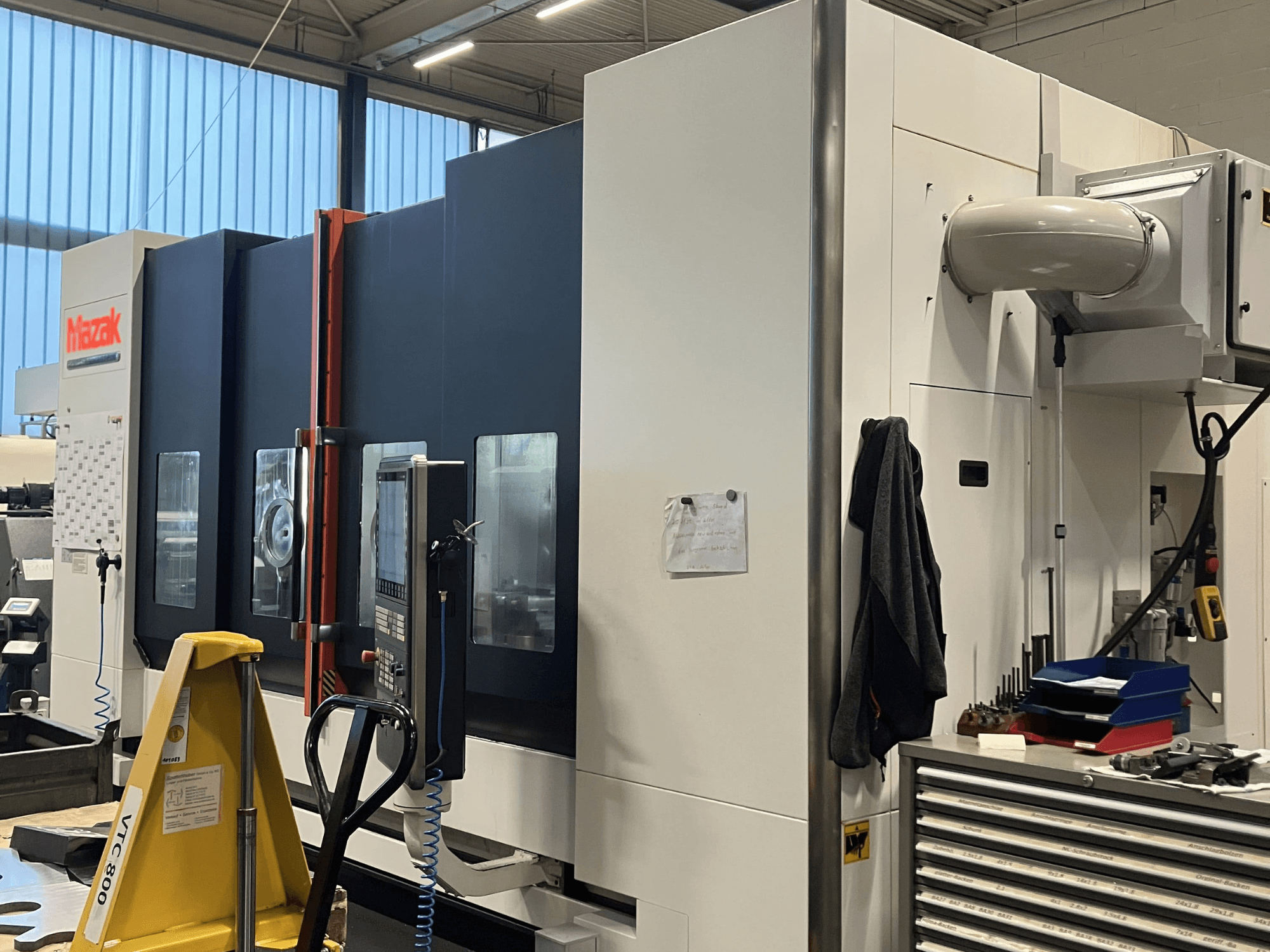 Mazak CNC machine viewed from the side, showcasing control panel and safety features in a workshop setting.