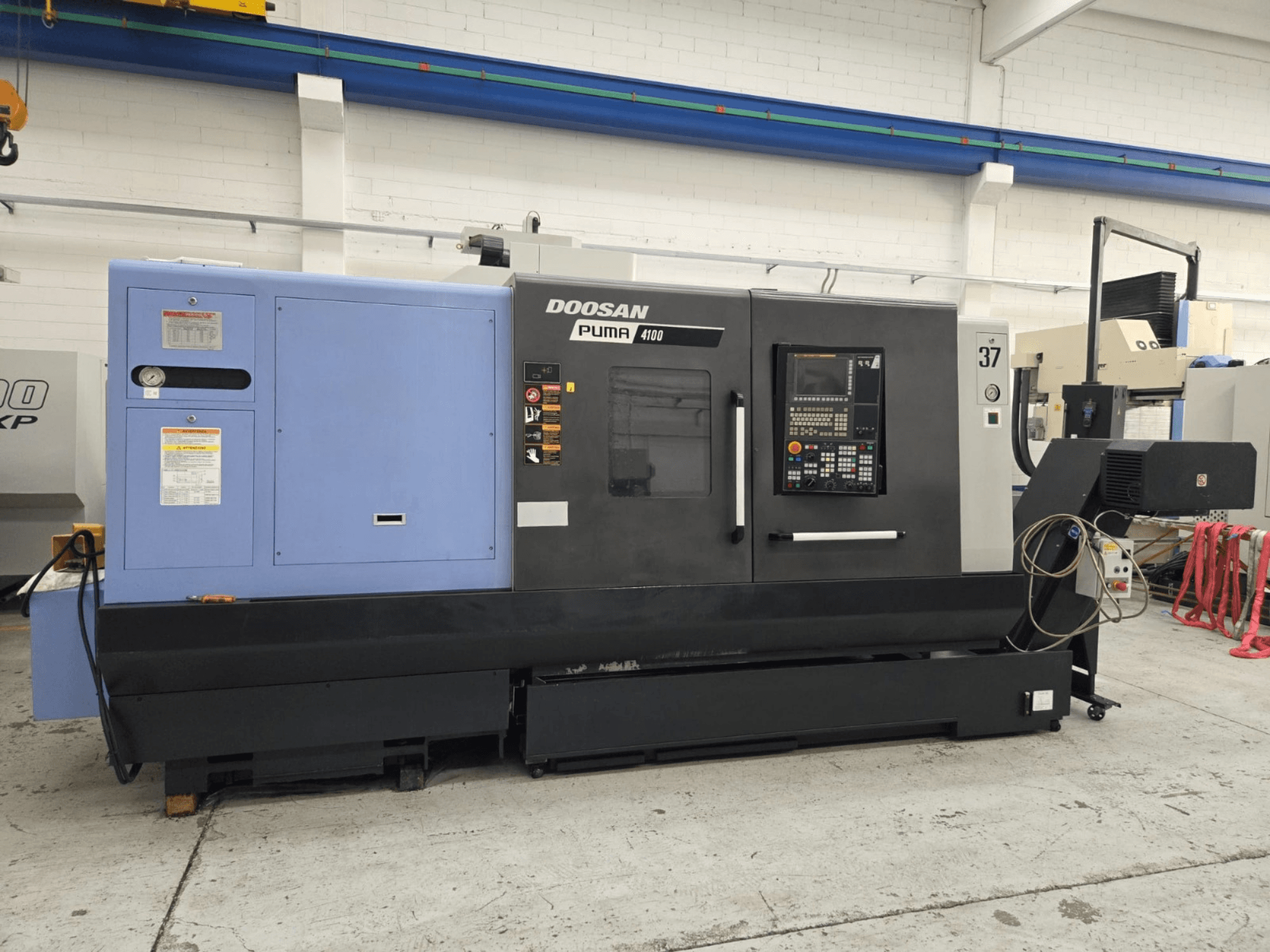 Torno CNC Doosan Puma 4100, vista frontal; incluye panel de control, unidad de potencia azul y etiquetas detalladas para orientación operativa.