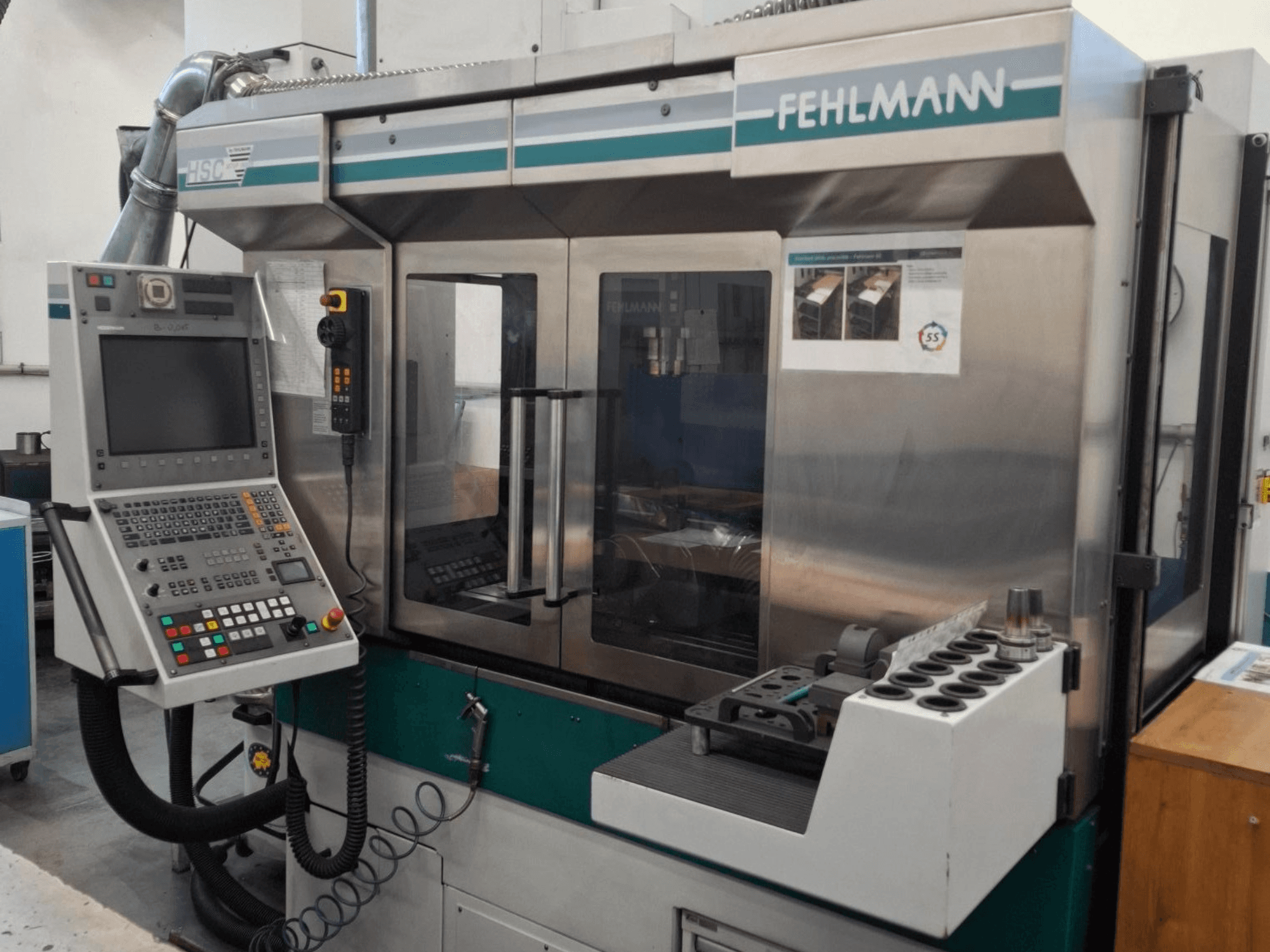 Máquina CNC Fehlmann HSC 20, vista frontal, con panel de control, carcasa metálica y portaherramientas con múltiples ranuras.