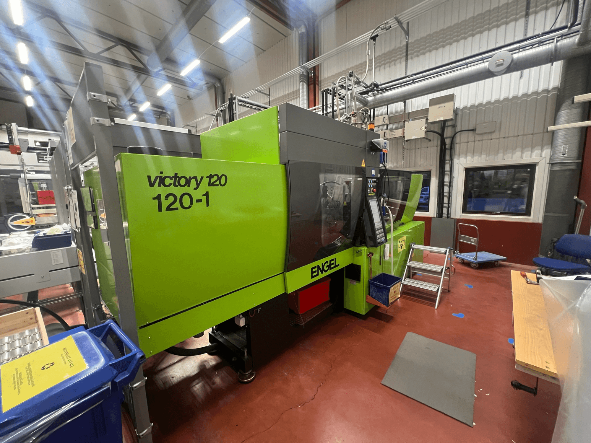 Máquina de moldeo por inyección ENGEL Victory 120-1 verde, vista frontal, con panel de control y escalones, en un entorno industrial.