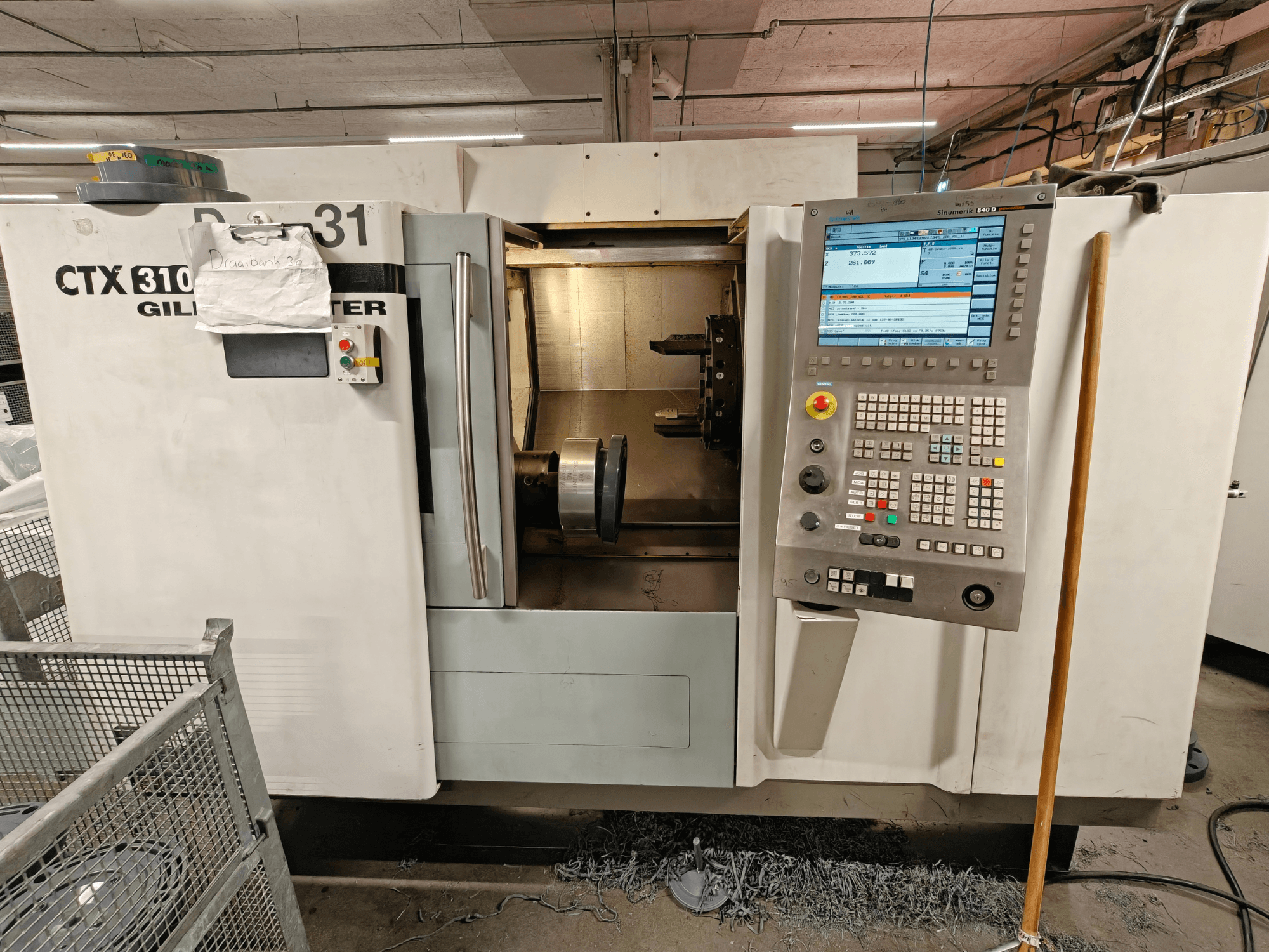 Tornos horizontales Gildemeister CTX 310, vista frontal con panel de control, mostrando herramientas y espacio de trabajo en el interior.