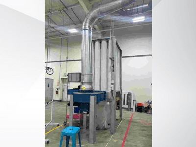 Gran sistema de ventilación industrial, vista frontal, con conductos de metal brillante y base azul, situado en un amplio almacén.