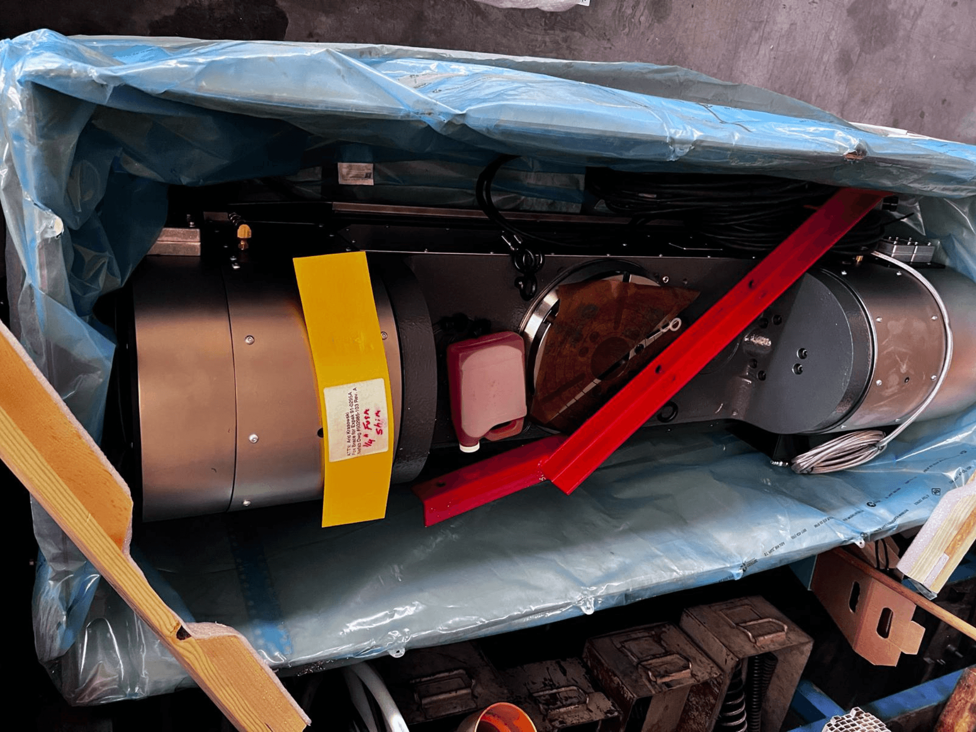 Motor device partially visible in packaging, features a silver exterior, colorful gauges, and red support brace.