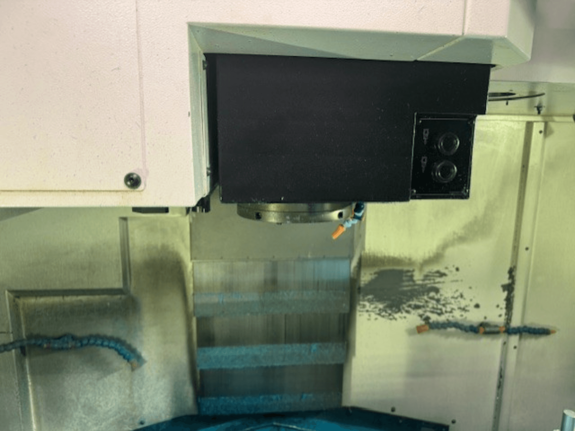 Primer plano del panel de control y el portaherramientas de una fresadora CNC, mostrando los detalles de la marca, los botones y la superficie de trabajo.