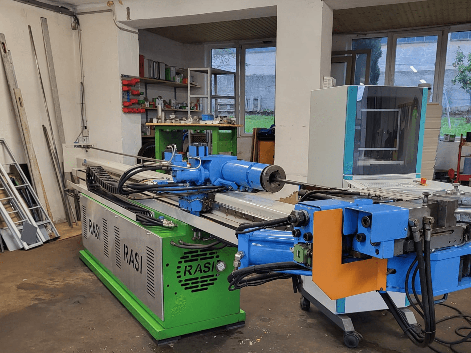Máquina herramienta Rasi S 80.6 L G-V3C50 en un taller, vista lateral mostrando los componentes azules y verdes y el panel de control.