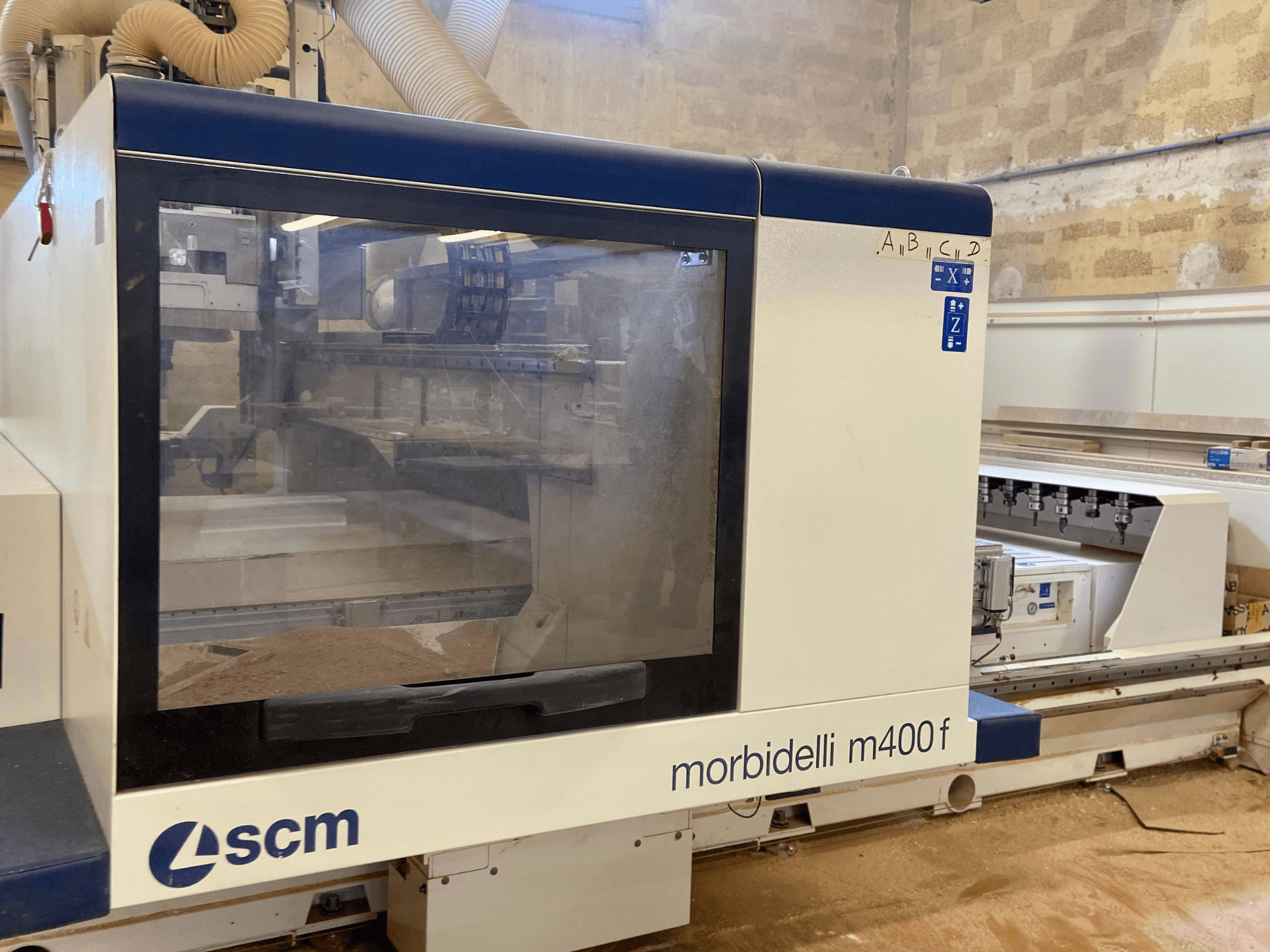 Máquina CNC SCM Morbidelli M400F, vista frontal, con un panel de control y serrín visible en el suelo.