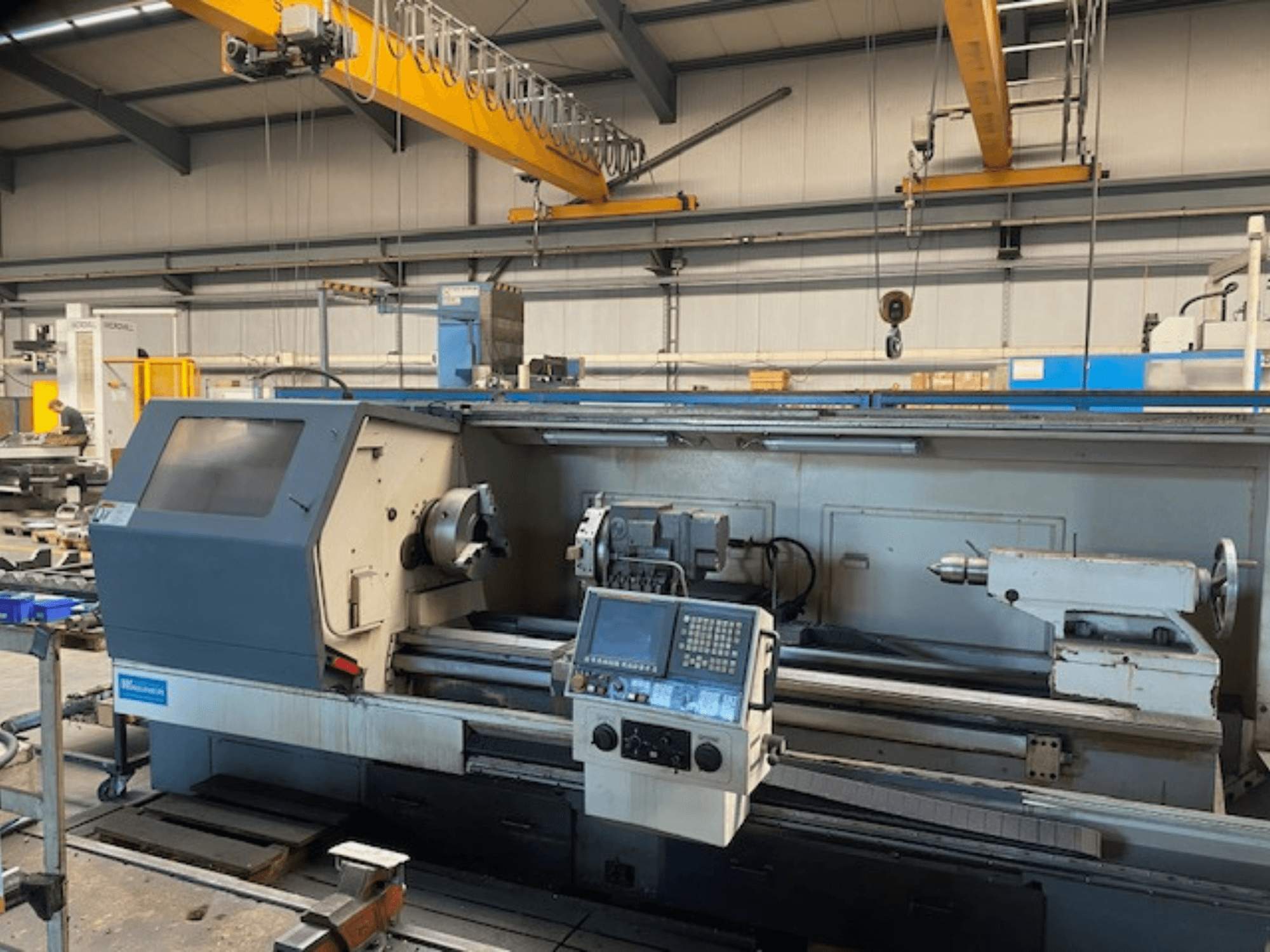 Torno de precisión Wabeco, vista frontal con panel de control, mostrando la configuración del husillo y las herramientas en un entorno de fábrica.