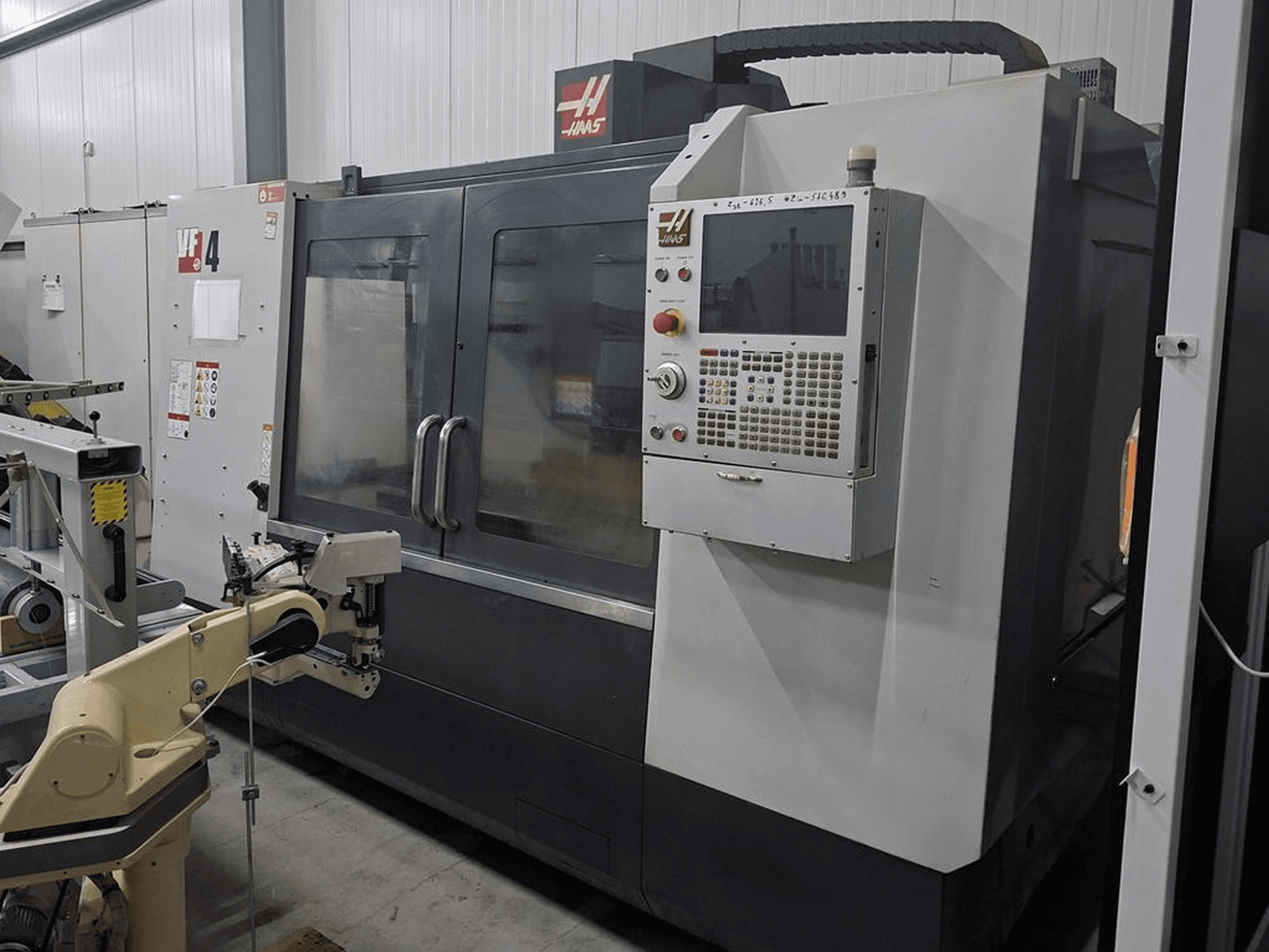Haas VF-4 CNC milling machine in front view, featuring a numerical control panel and robotic arm for automation.