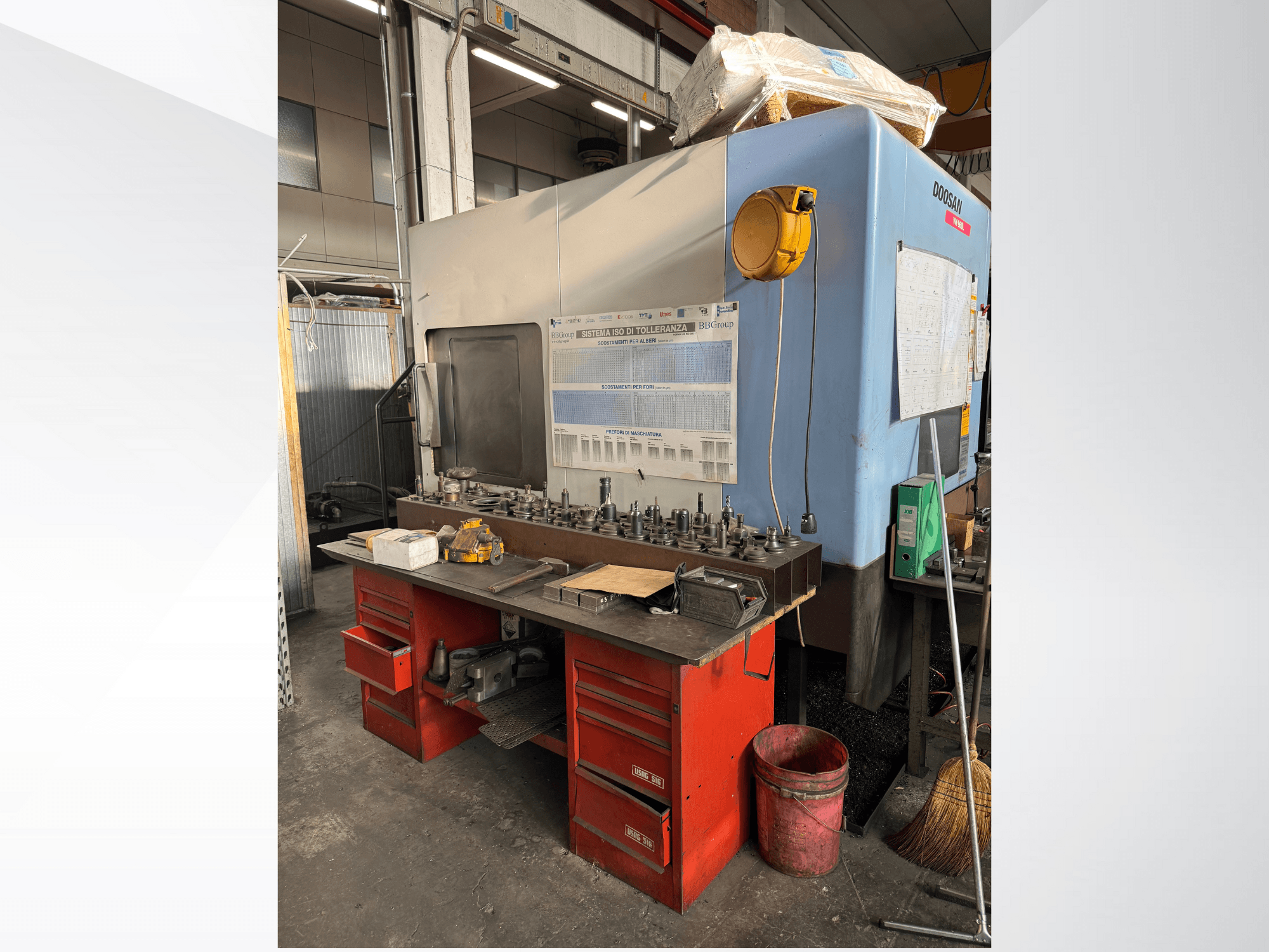 Doosan machining center with a red workbench and storage, displaying tools and equipment, viewed from the front.