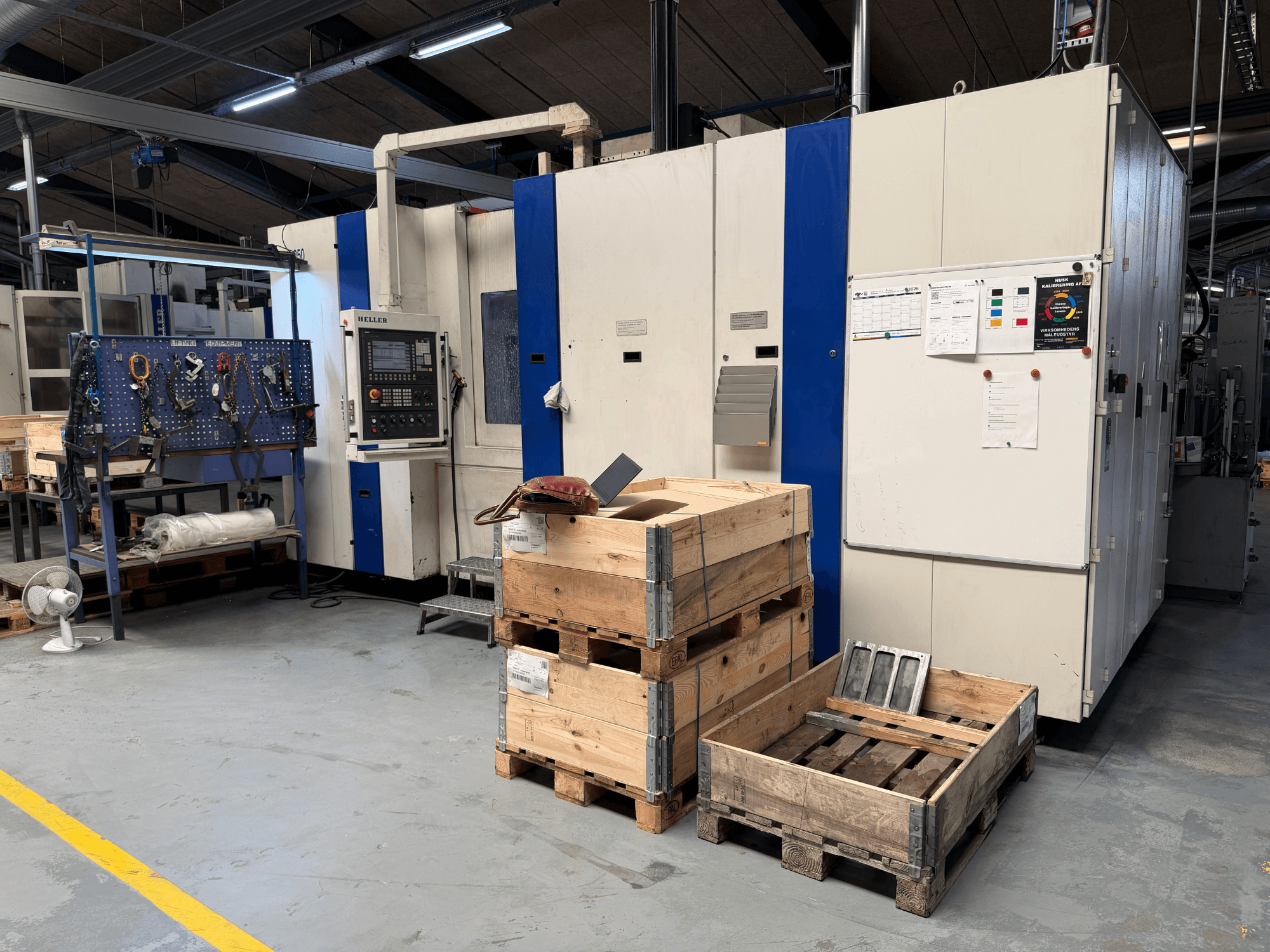 CENTRO DE MECANIZADO HORIZONTAL HELLER MCH 250 en taller, vista lateral con palets de madera y estante de herramientas visible.