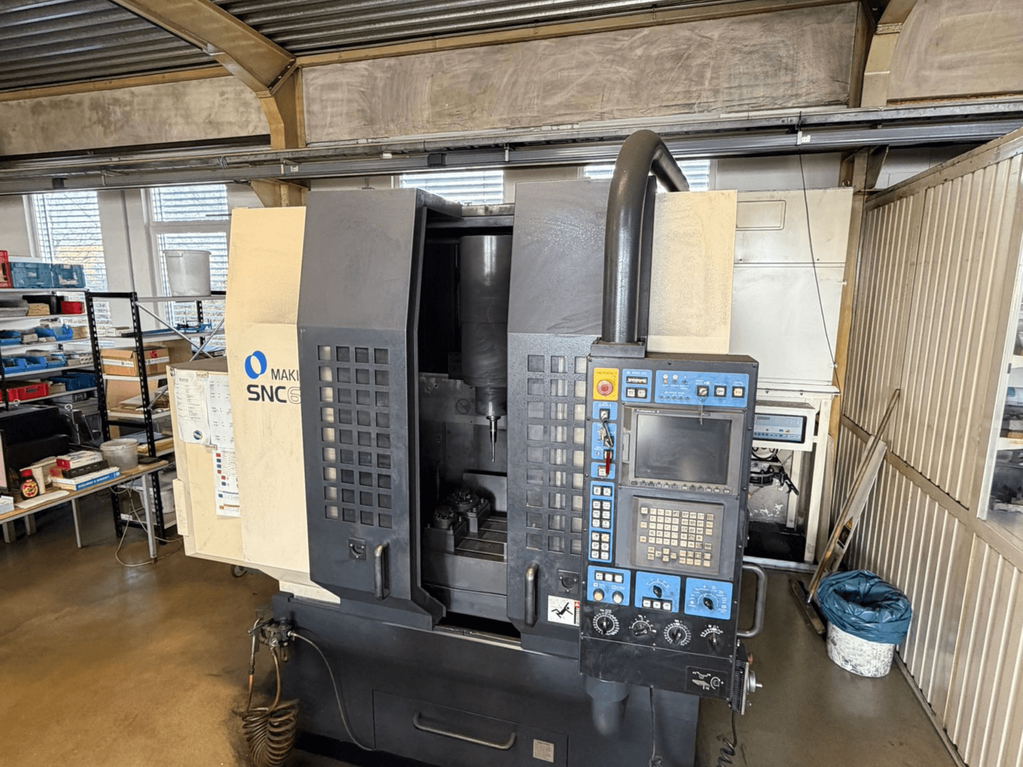 Centro de mecanizado vertical Makino SNC 64-A15 en vista frontal, mostrando el panel de control, el área de mecanizado y el espacio de trabajo industrial.
