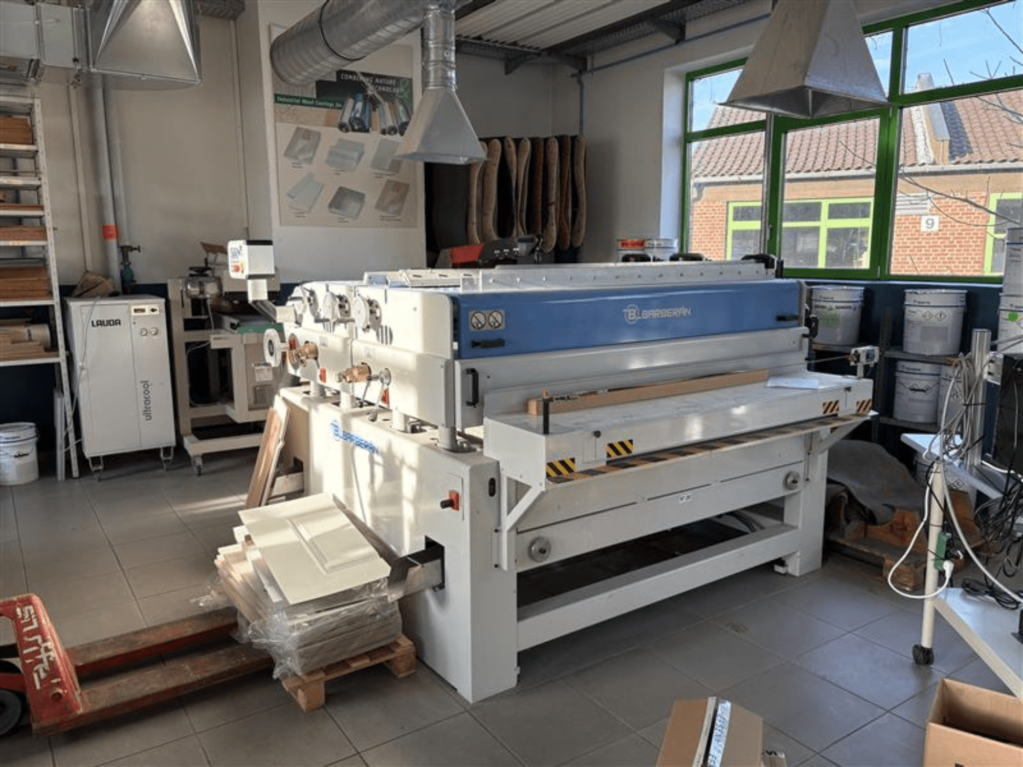 Blaserbn woodworking machine in a workshop, front view; with wooden panels on a pallet and modern equipment in the background.