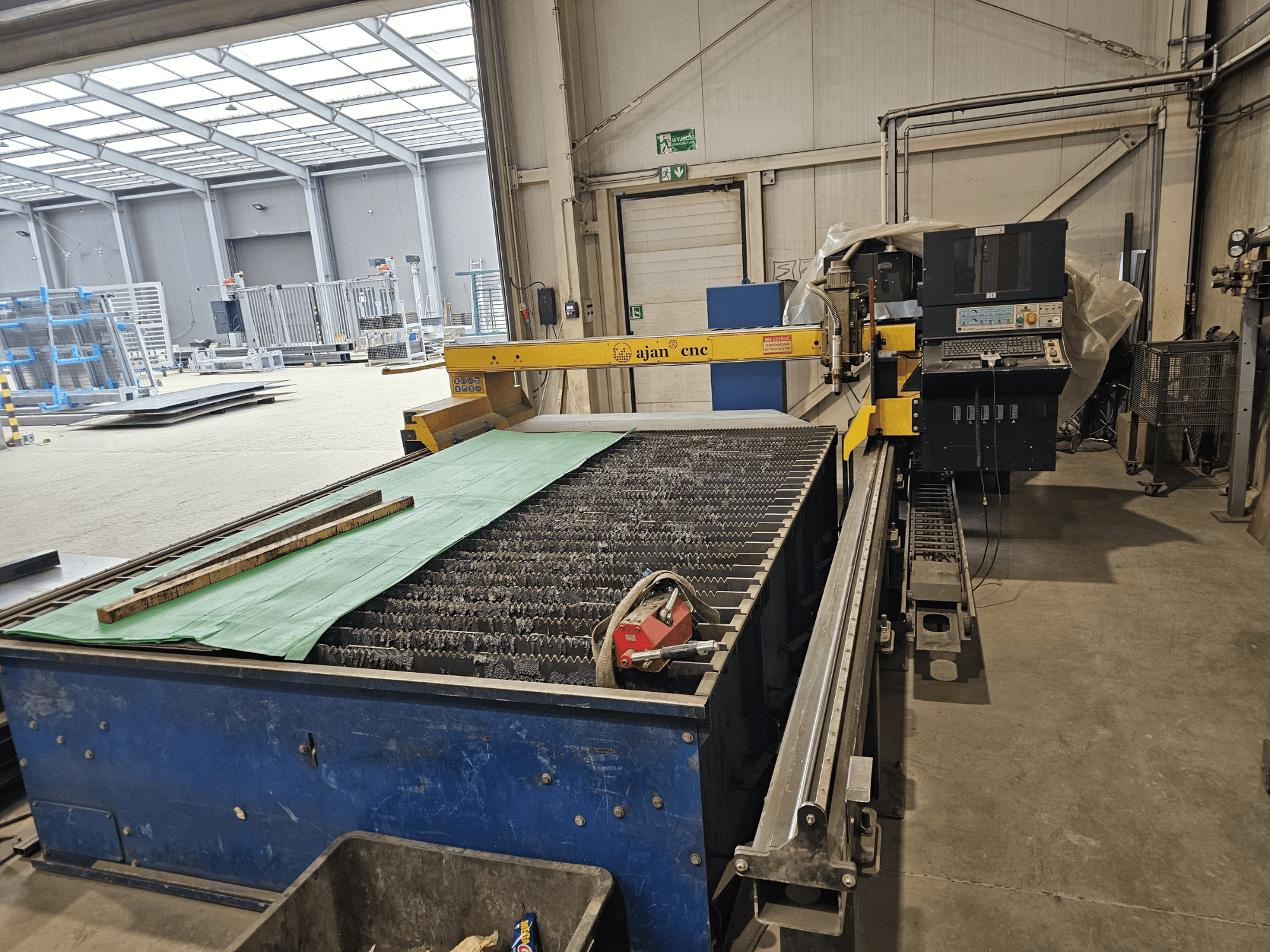 AJAN PP16011 Máquina de corte por plasma automática en vista lateral, con mesa de corte y panel de control, situada en un entorno de taller.