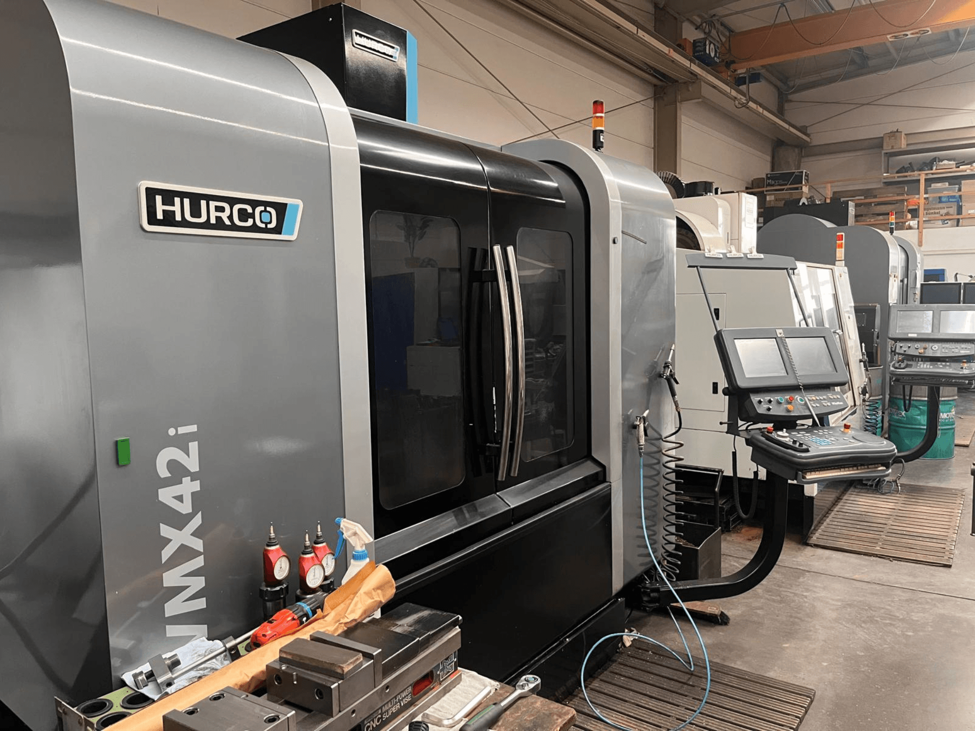 Máquina CNC Hurco VMX42i en un taller, vista frontal, con panel de control y varias herramientas en el banco de trabajo.